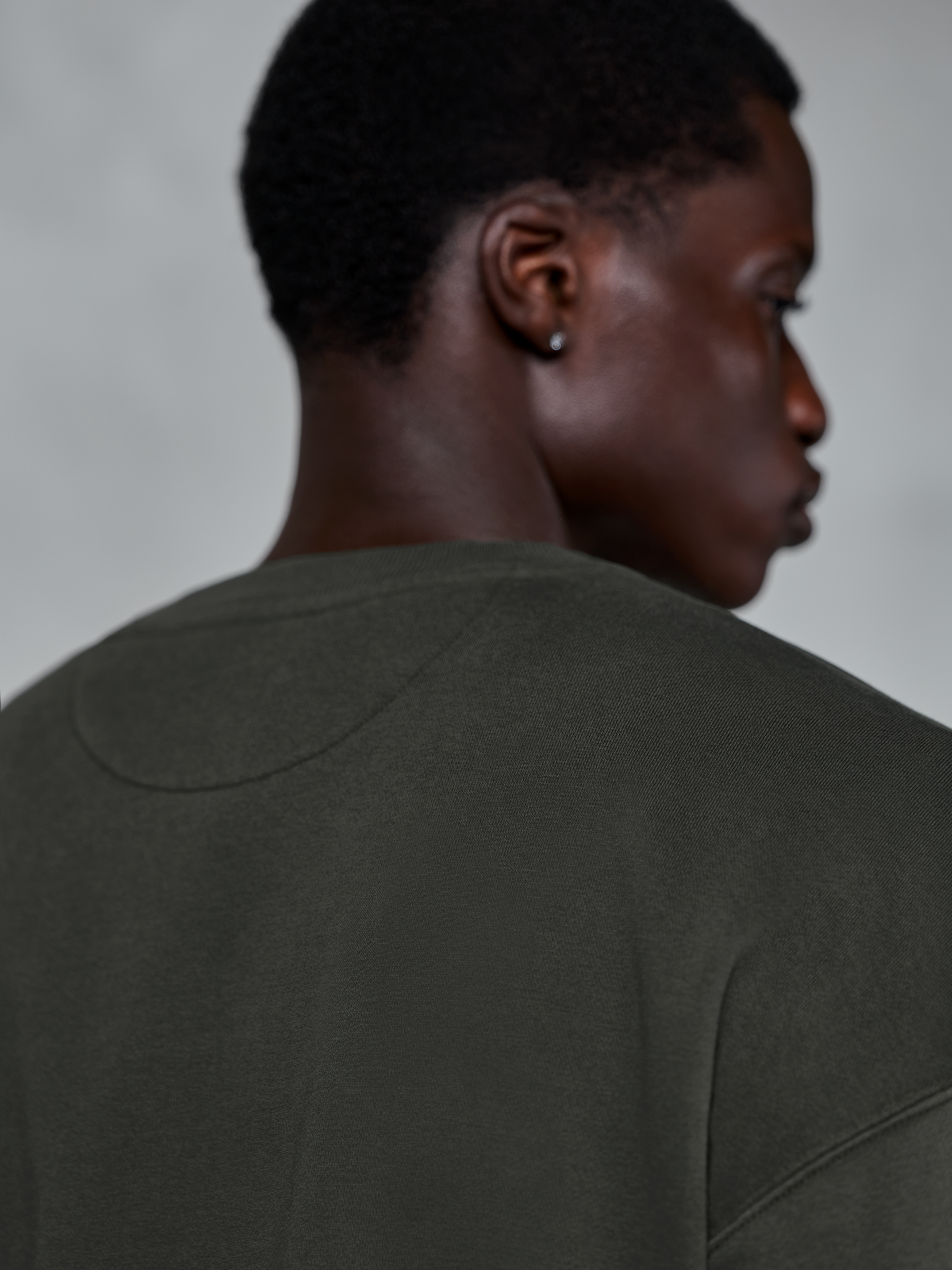 Alpinestars Essentials Ageless Crew, premium crewneck sweatshirt in Off Black, close-up view of the back neckline and shoulder area, garment stone washed compact fleece texture, casual motorsport-inspired streetwear