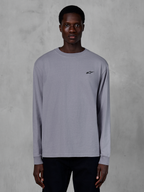 Alpinestars Essentials Ageless LS Tee, långärmad t-shirt, silver, bärs av en modell, med en liten svart Alpinestars-logotyp på bröstet, avslappnad modern passform, streetwear i ekologisk bomull