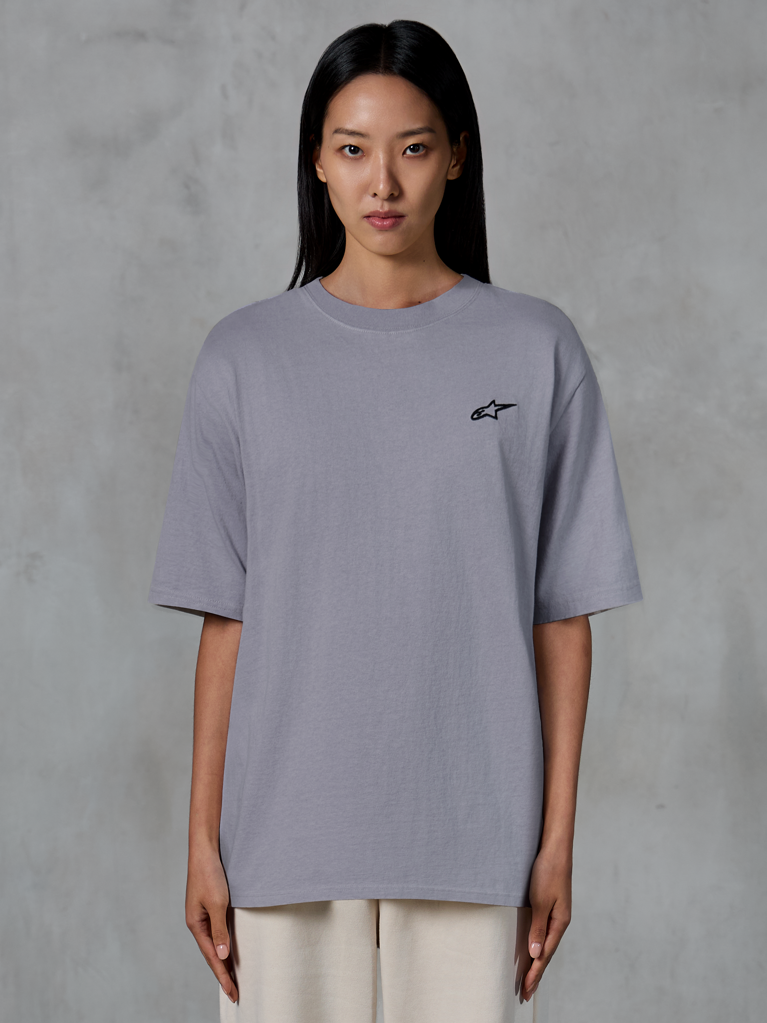 Alpinestars Essentials Ageless SS Tee, kortärmad t-shirt, silver, med en liten svart Alpinestars-logotyp på bröstet, avslappnad modern passform, ekologisk bomull, avslappnad lifestyle-streetwear buren av en modell
