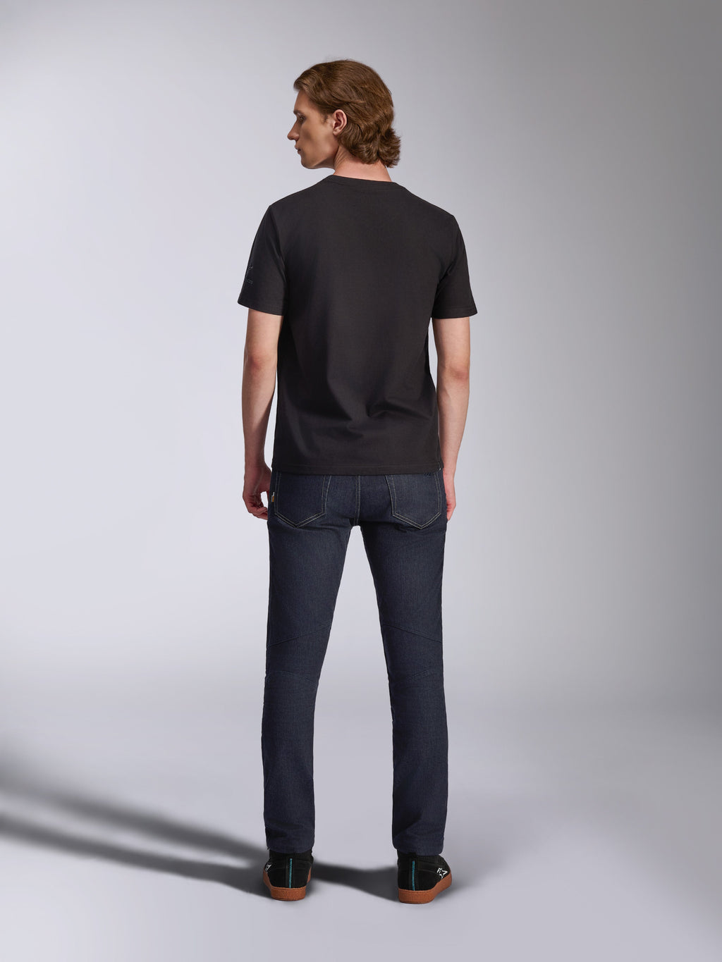 Alpinestars Global CSF T-shirt, kortärmad tröja i svart, ryggvy av manlig modell som bär t-shirten med mörka jeans, avslappnat motorsportinspirerat streetwear