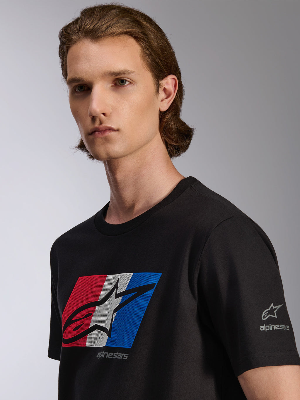 Alpinestars Global CSF T-shirt, kortärmad t-shirt, svart, röd, vit och blå grafik med svart shadow-logotyp, detaljvy på modell, casual motorsport streetwear