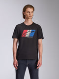 Alpinestars Global CSF Tee, kortärmad t-shirt, svart, röd, vit och blå Ageless-logotypgrafik, bärs av manlig modell med mörka jeans, avslappnad motorsport-streetwear