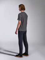 Alpinestars Waving CSF Tee, kortärmad t-shirt, charcoal, sedd bakifrån på modell, liten svart stjärnlogotyp på ärmen, bärs med mörka denimjeans och svarta sneakers, avslappnad motorsport-streetwear