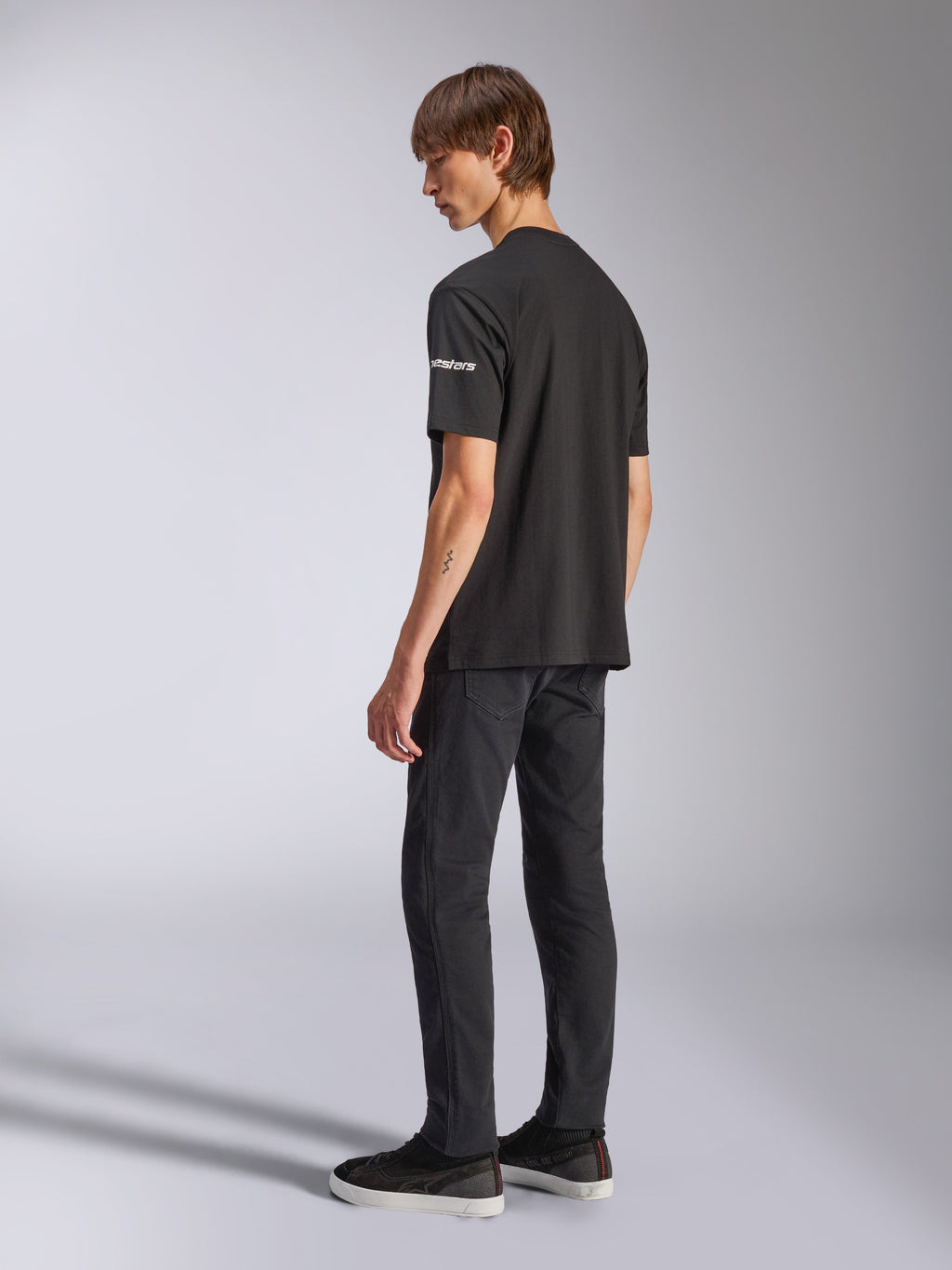 Alpinestars Frontal CSF Tee, kortärmad t-shirt, svart, vit astars-logotyp på ärmen, bärs av modell med svarta byxor och skor, avslappnad motorsportinspirerad design