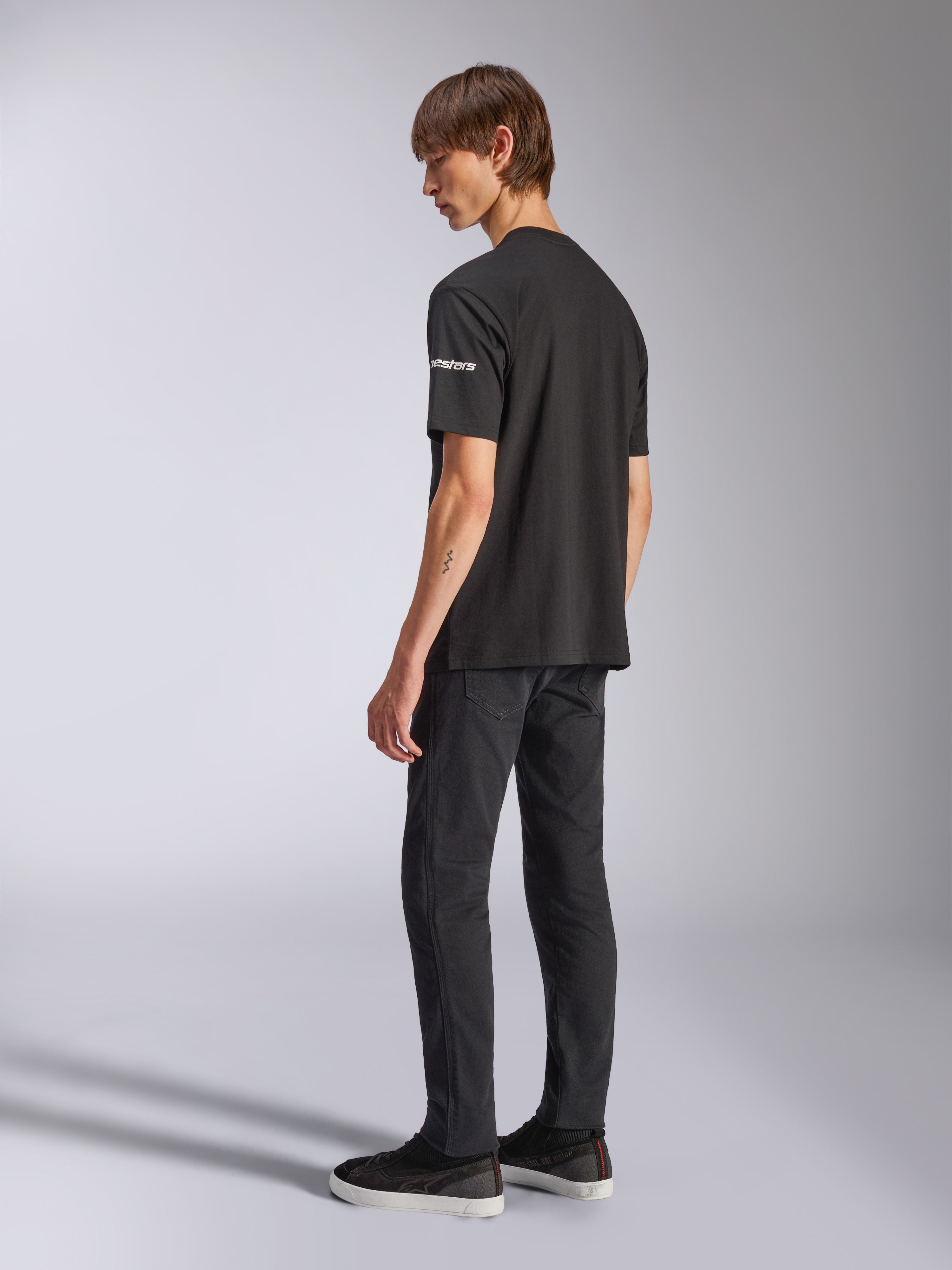 Alpinestars Frontal CSF Tee, kortärmad t-shirt, svart, vit astars-logotyp på ärmen, bärs av modell med svarta byxor och skor, avslappnad motorsportinspirerad design