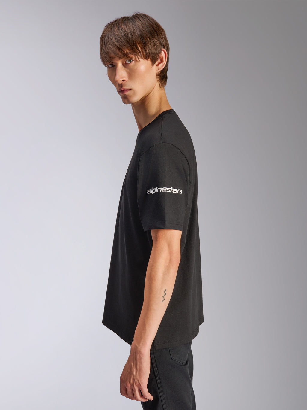 Alpinestars Frontal CSF Tee, kortärmad t-shirt, svart, vit Alpinestars-logotyp på ärmen, bärs av modell i profilvy, casual motorsport performance streetwear