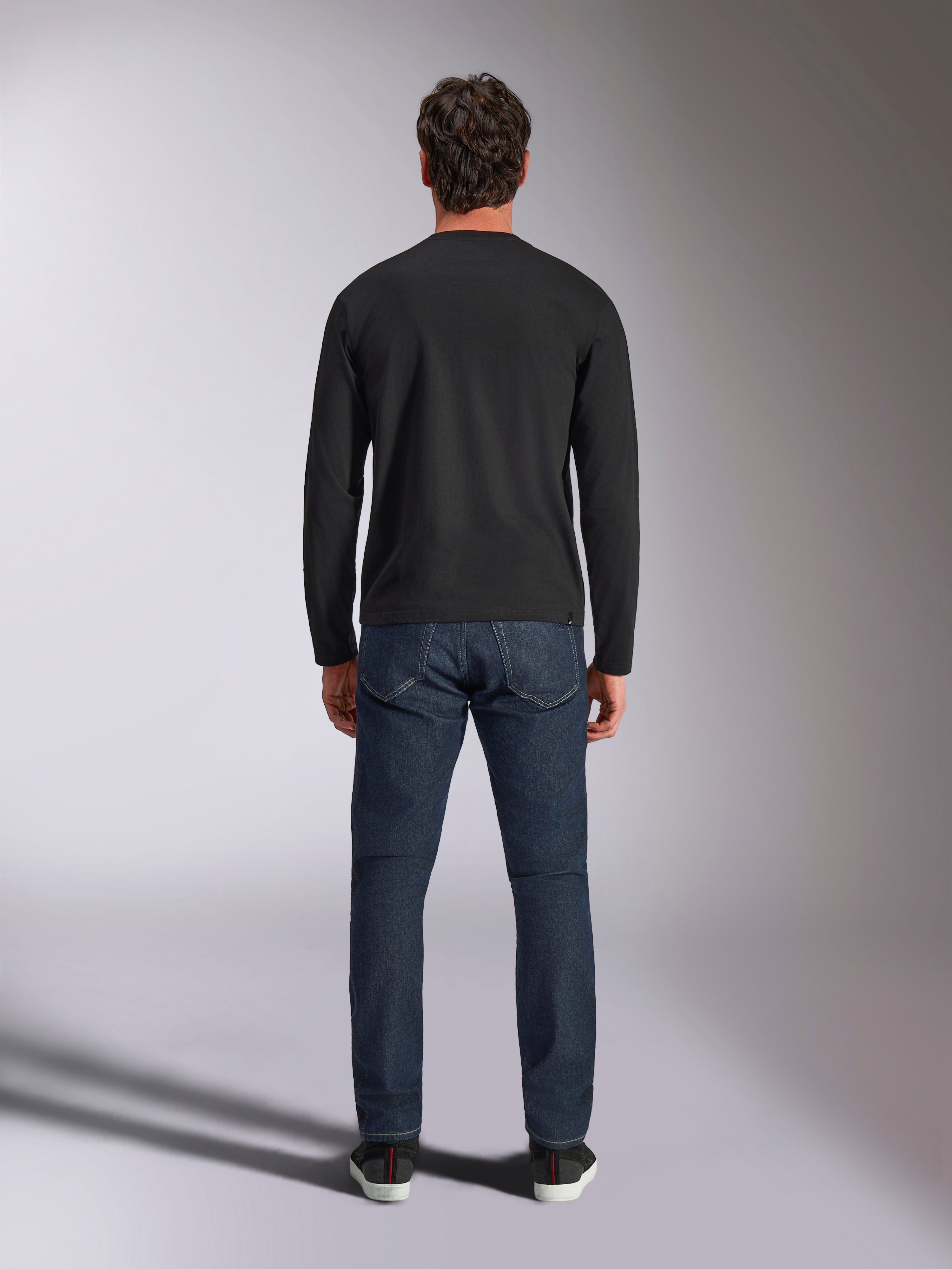 Alpinestars Trackside CSF Tee, långärmad t-shirt, svart, sedd bakifrån på en modell i mörkblå denimjeans, casual motorsport-streetwear