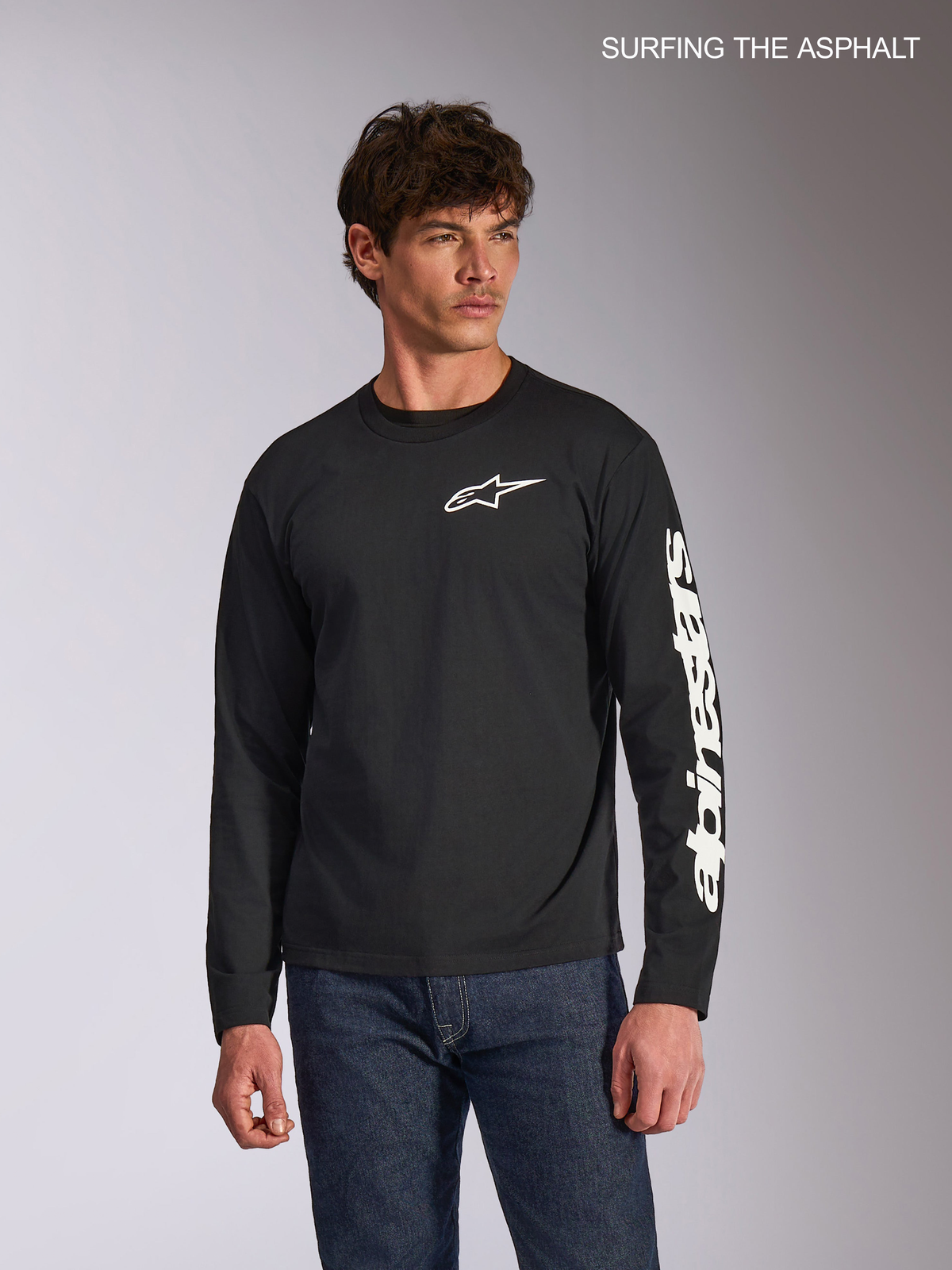 Alpinestars Trackside CSF långärmad t-shirt, svart vardagströja med vit Ride 4.0-logotyp på bröstet och tryckt branding på ärmen, bärs av en modell med jeans