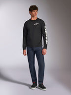 Alpinestars Trackside CSF Tee, långärmad t-shirt, svart och vit, bärs med mörkblå jeans och svarta sneakers, med vit Ride 4.0-logotyp på bröstet och Alpinestars ordmärke på ärmen, motorsportinspirerat streetwear