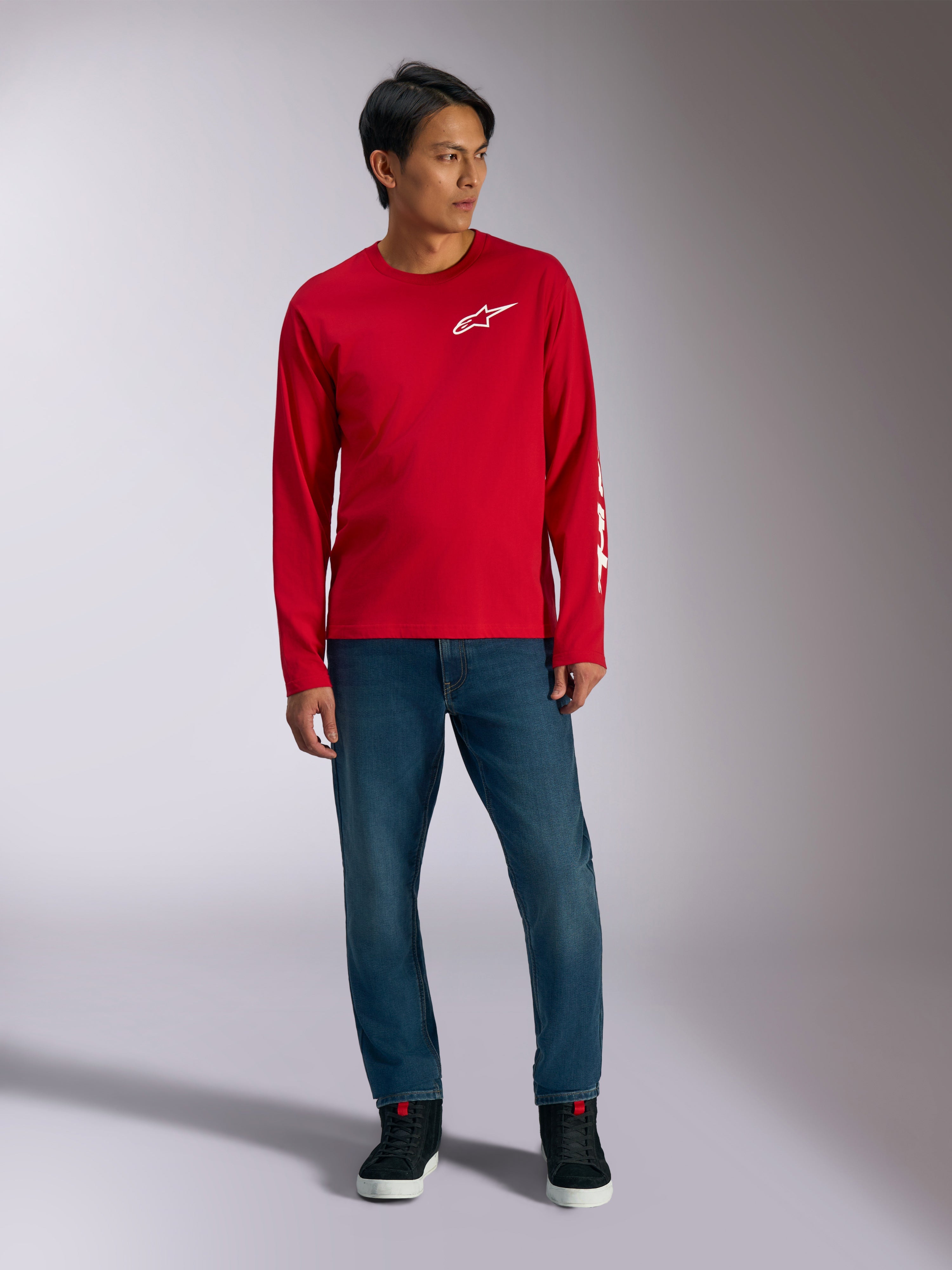 Alpinestars Trackside CSF Tee, långärmad t-shirt, röd med vit Alpinestars-logotyp, lifestyle-bild buren med blå jeans och svarta sneakers, avslappnade motorsportinspirerade sportkläder