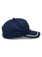 Alpinestars Ascension Snapback-keps, sidovy, marinblå med guld- och vit soutache-kant på den böjda skärmen, strukturerad krona, avslappnad motorsport-huvudbonad