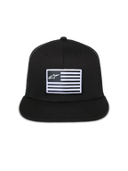 Alpinestars Flag Flat Trucker Hat, Black, flat-brim cap with structured crown, central rectangular patch with white flag and Alpinestars logo, mesh back, casual motorsport-inspired streetwear