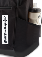 Alpinestars Defcon V3 Ryggsäck, svart ryggsäck för vardagsbruk, närbild av sidoficka i mesh med vattenflaska, vertikal vit logotyp på framsidan, hållbart 600D-polyestermaterial