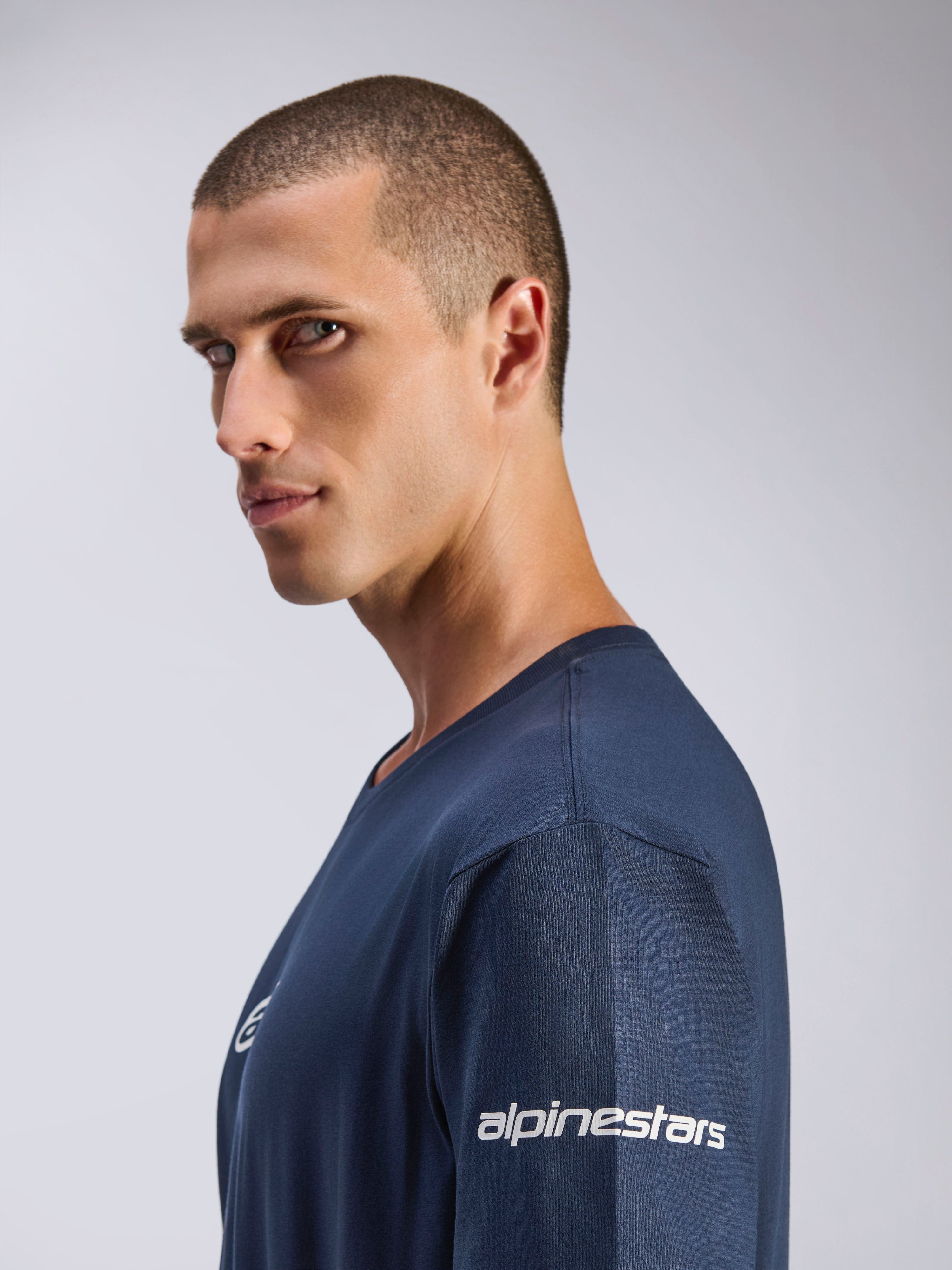Alpinestars Frontal CSF Tee, Short Sleeve T-Shirt, Navy Blue, side profile view of male model, white Alpinestars logo on sleeve, performance moisture-wicking fabric, casual motorsport lifestyle