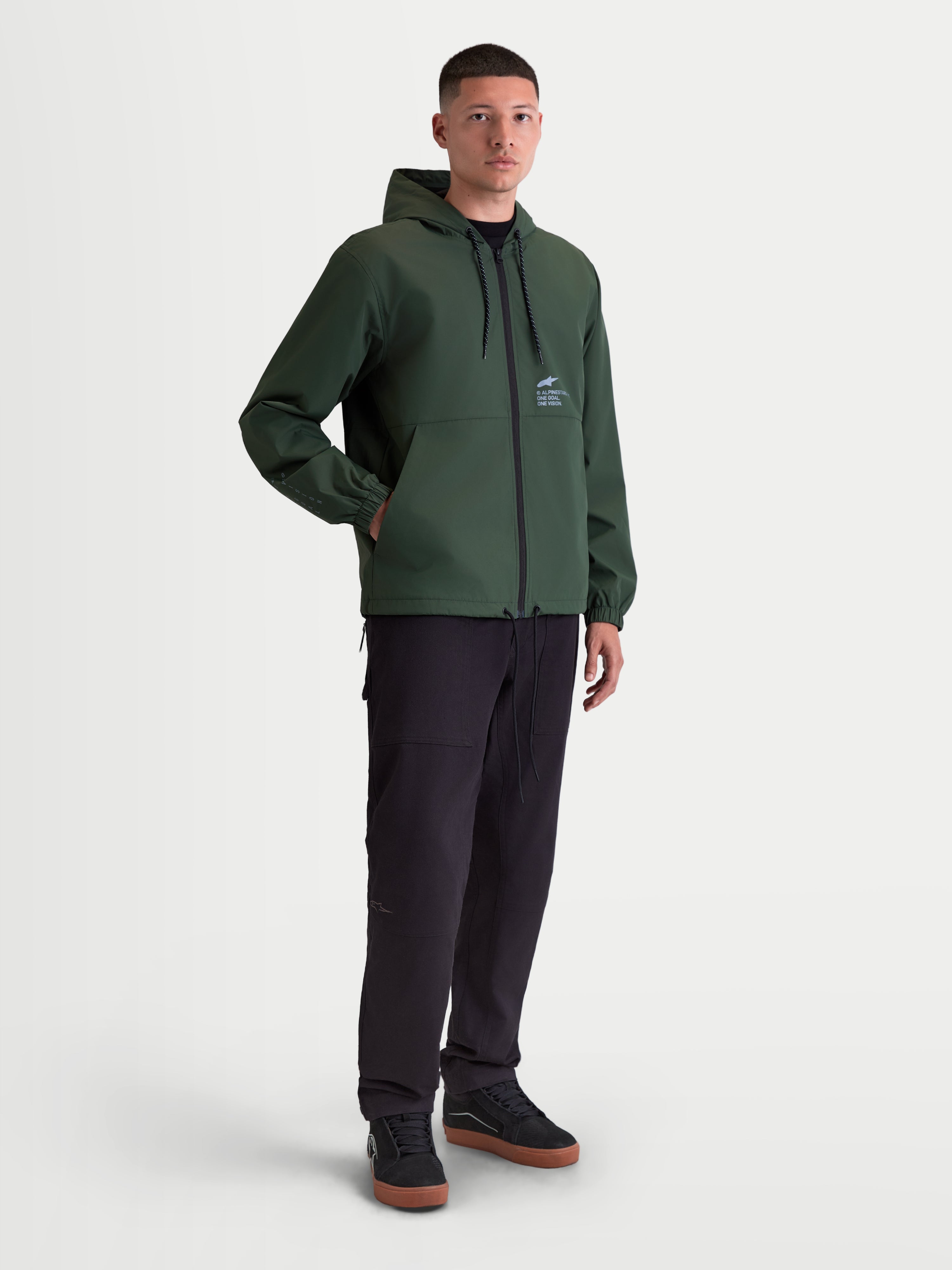 Alpinestars Speeder Resolve vindstopp jacka, lätt vindjacka för herr, grön, med justerbar huva och meshfoder, idealisk för urban användning, motorsportinspirerad design med Alpinestars-logotyp på bröstet