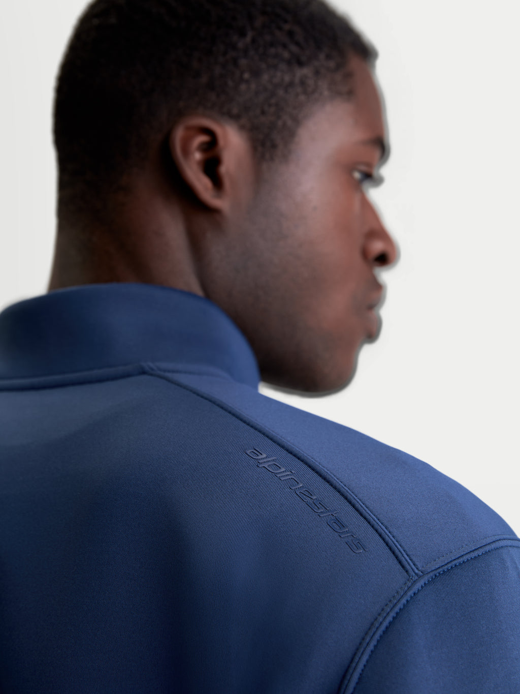 Alpinestars Apera half-zip sweatshirt, blå sportswear-tröja, detaljbild på axel som visar tonat HD-logotryck och premium tri-blend fleecetyg, motorsport-inspirerad design.