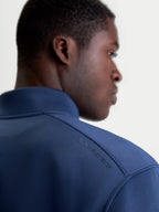 Alpinestars Apera half-zip sweatshirt, blå sportswear-tröja, detaljbild på axel som visar tonat HD-logotryck och premium tri-blend fleecetyg, motorsport-inspirerad design.