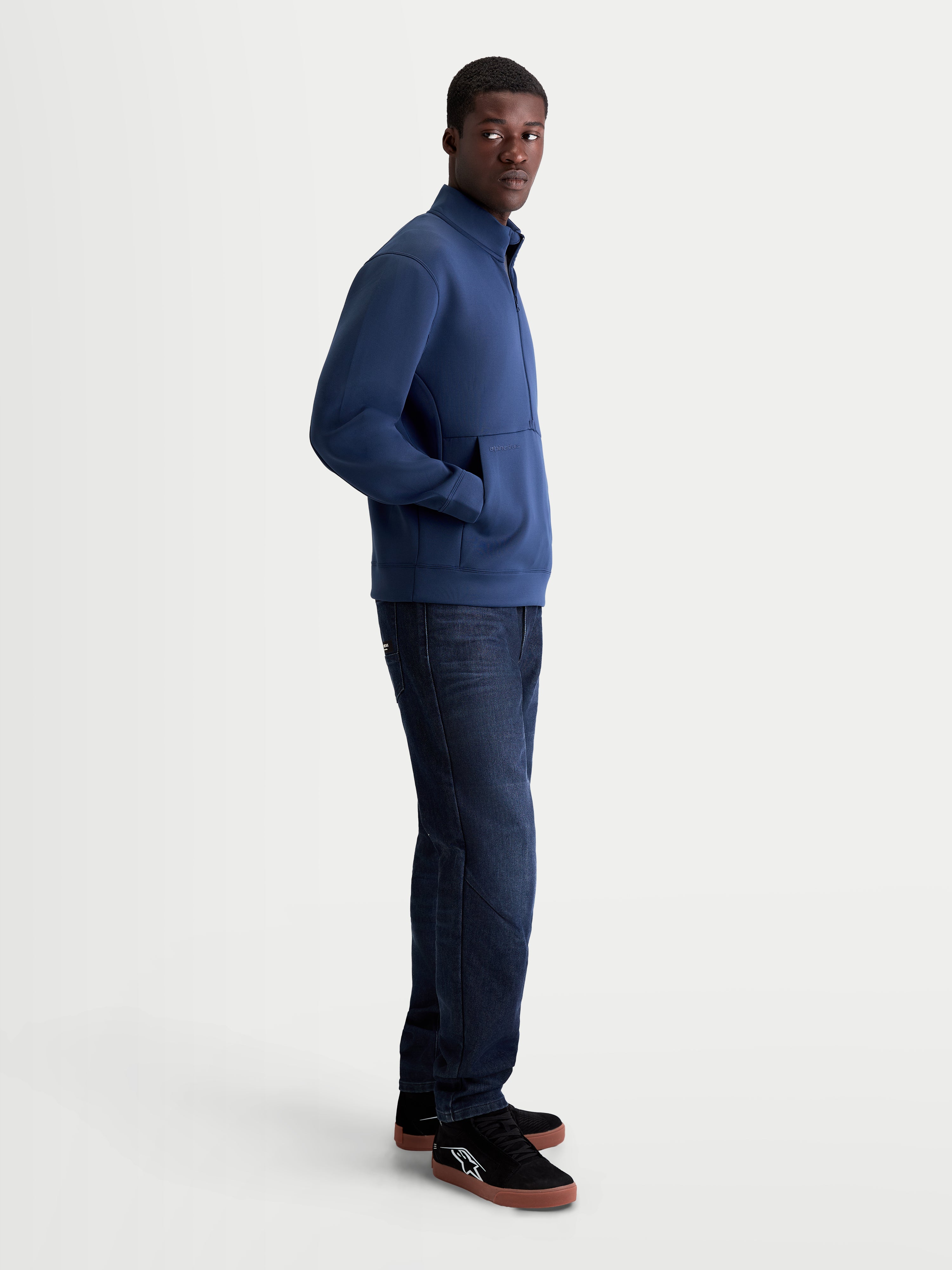 Alpinestars Apera half-zip sweatshirt på modell sedd från sidan, stålblå herrtröja i tri-blend-fleece med känguruficka, motorsportinspirerad stil för vardagsbruk