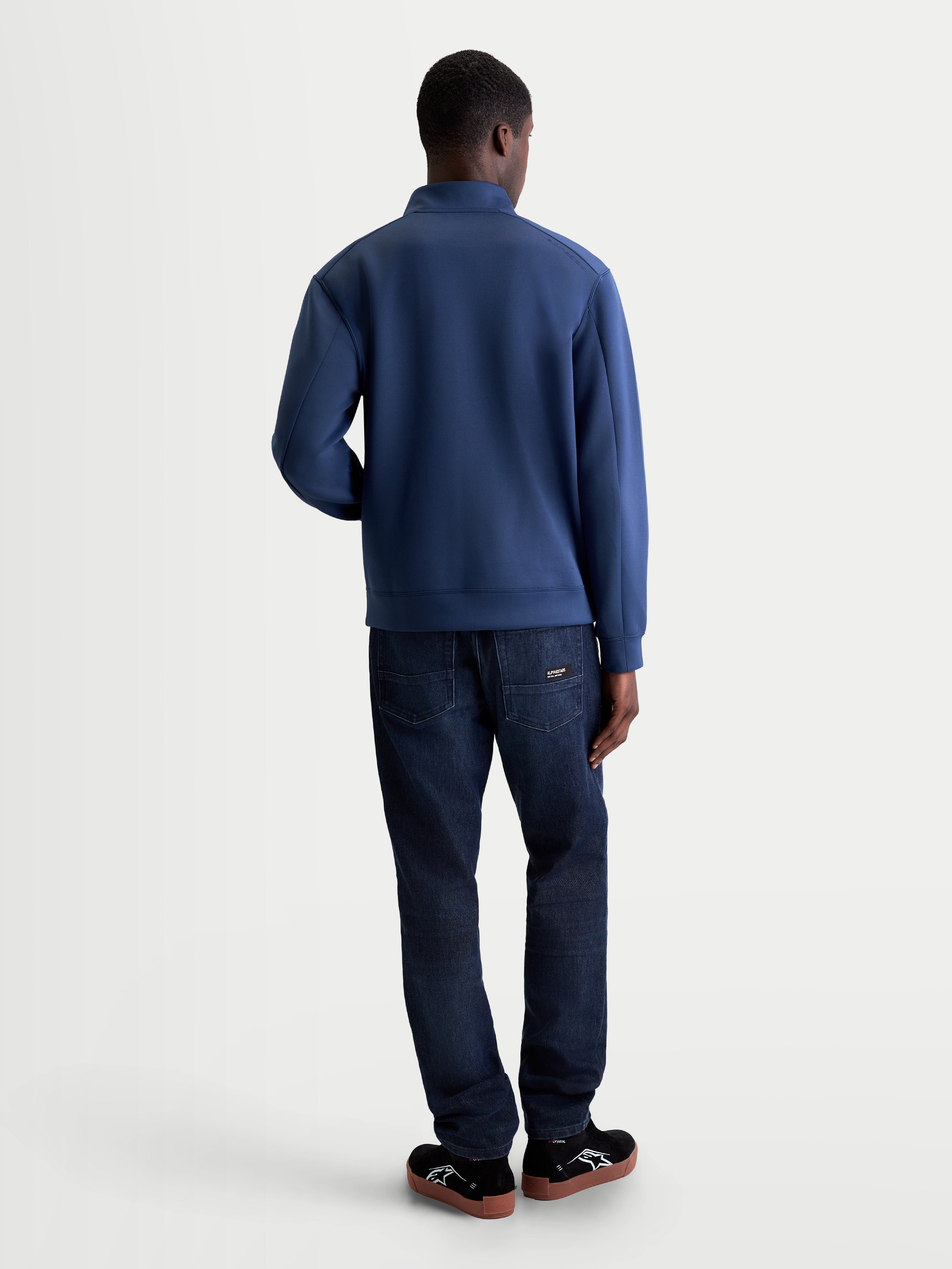 Alpinestars Apera Half-Zip sweatshirt, blå motorsportinspirerad herrtöja sedd bakifrån på modell, stilren design i tri-blend dubbelvävd fleece för vardagskomfort.