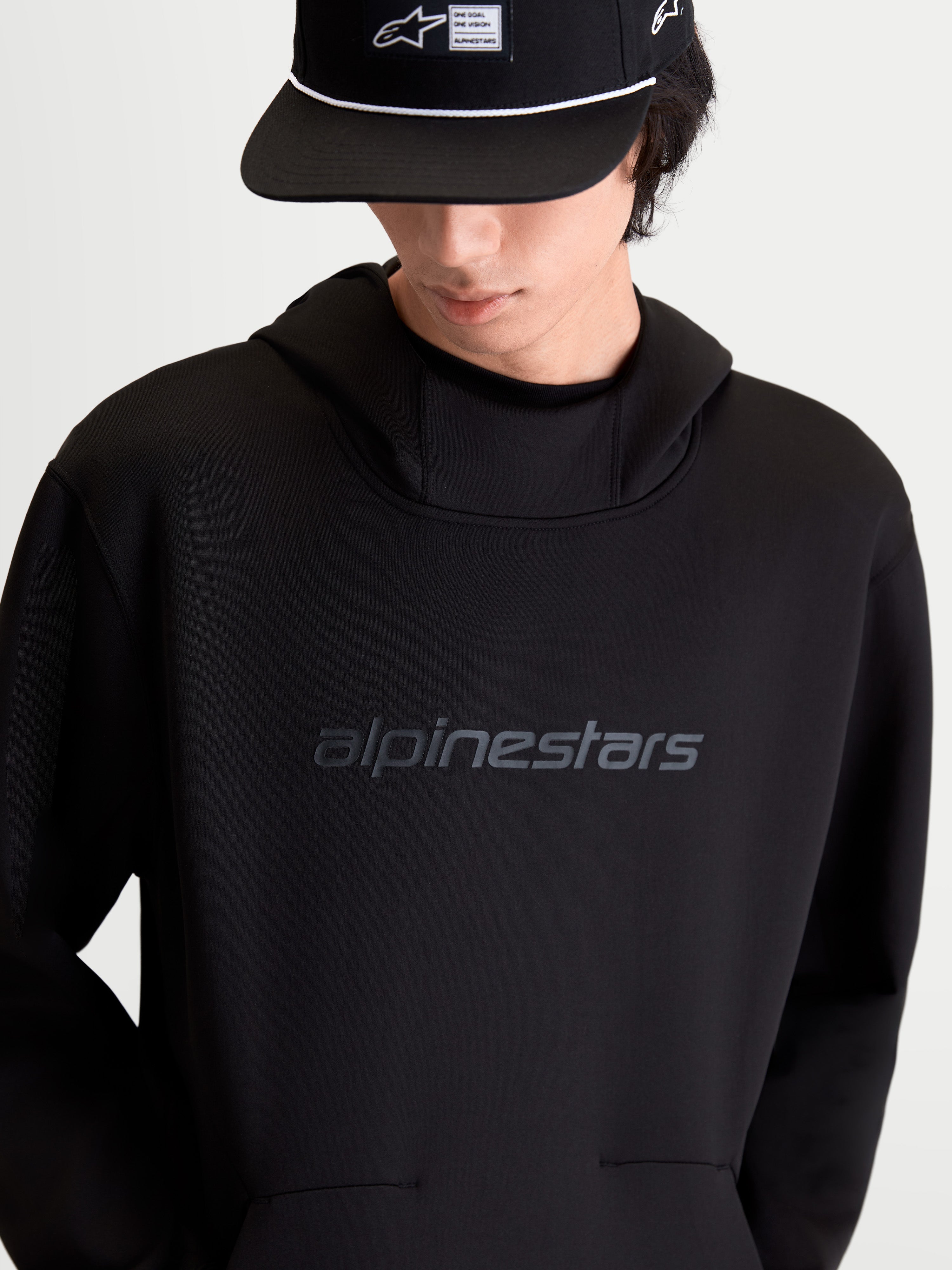 Alpinestars Datrix huvtröja, svart pullover för vardagsbruk och sportswear, tonal HD-logotyp på bröstet, meshfodrad huva och dubbelvävd tri-blend-fleece, sedd framifrån på modell.