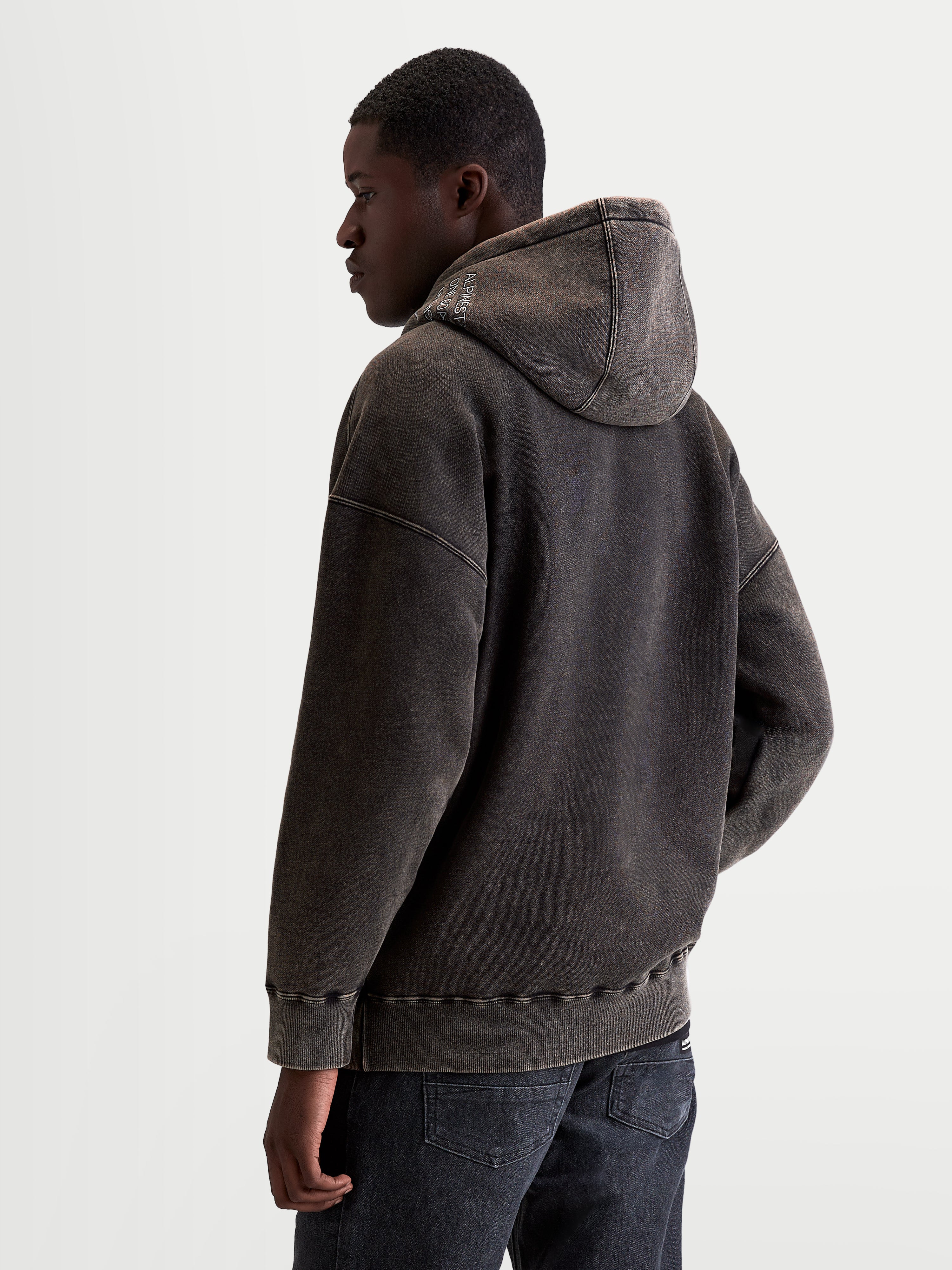 Alpinestars Infinite Washed Oversize huvtröja, oversized huvtröja för herrar i svart fleece med snötvättad finish, ryggvy på modell, broderad logotyp på huvan, avslappnad passform, sportswear.
