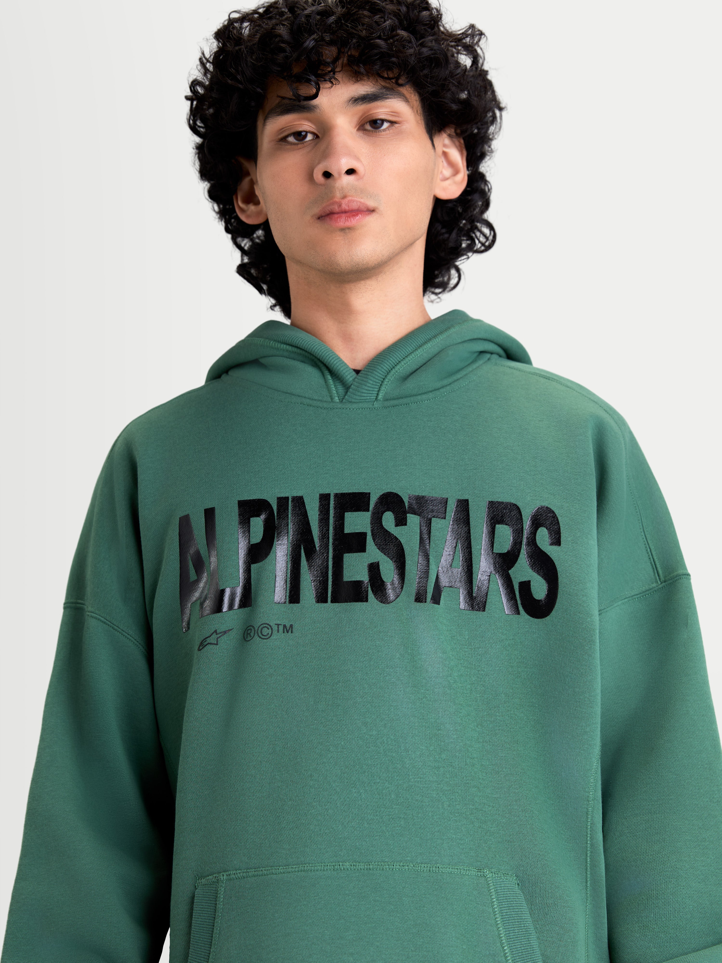 Alpinestars Shaw oversized huvtröja, grön huvtröja i sportswear-stil med en stor svart texturerad Alpinestars-logotyp på bröstet, avslappnad passform, mjuk fleece i bomull och återvunnen polyester.