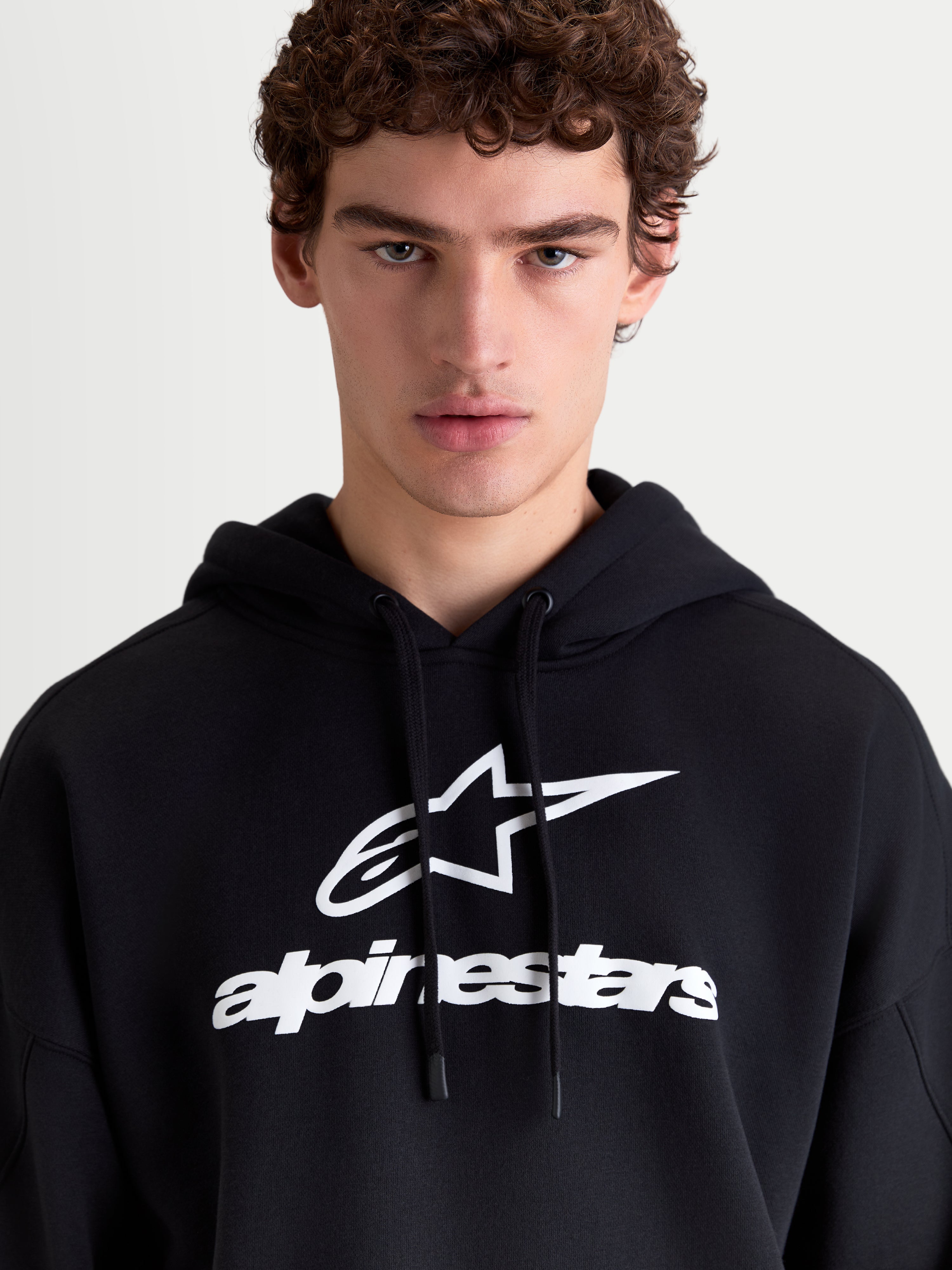 Alpinestars Prelude Oversized Hoodie, Sportswear Fleece Pullover, Black and White, featuring a bold puff-print chest logo, self-lined hood with flat drawcords, and a relaxed oversized fit for casual everyday comfort.