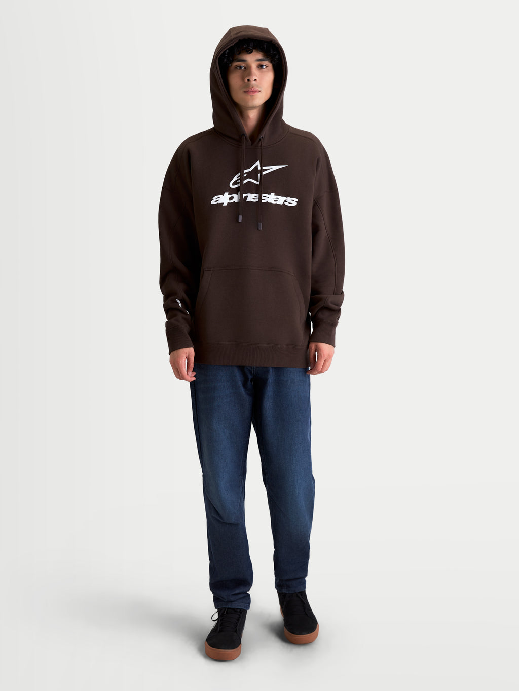 Alpinestars Prelude Oversized huvtröja, brun sportswear-fleecepullover, unisex, bomullsrikt material, avslappnad oversized passform, vit puff-printad logotyp på bröstet, känguruficka och fodrad huva, visas på modell.