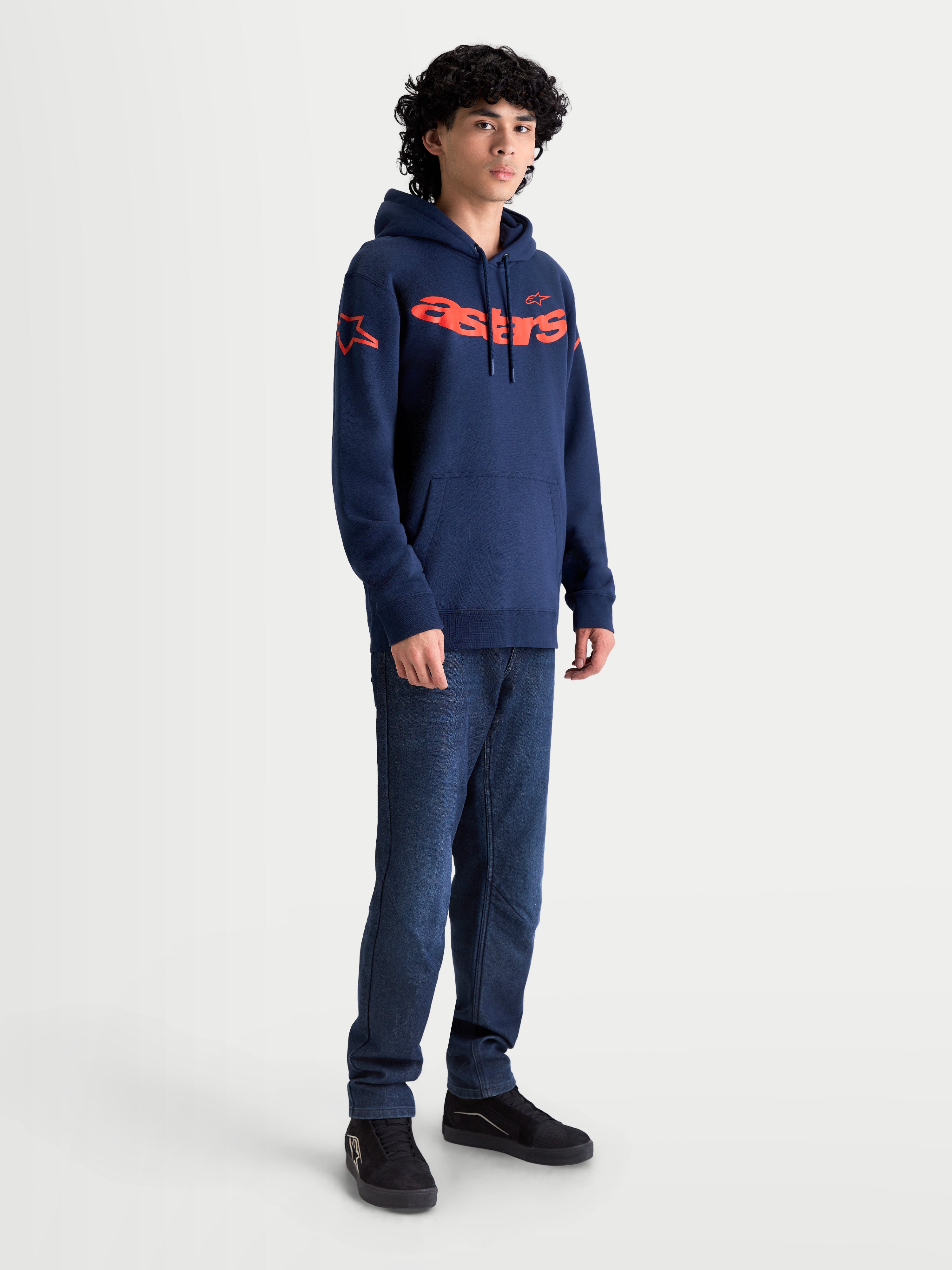Alpinestars Velocifier huvtröja, mörkblå och orange herrhuvtröja i fleece med tydlig Astars-text på bröstet och logotyper på axlarna, visas på modell för en avslappnad motorsportinspirerad stil.