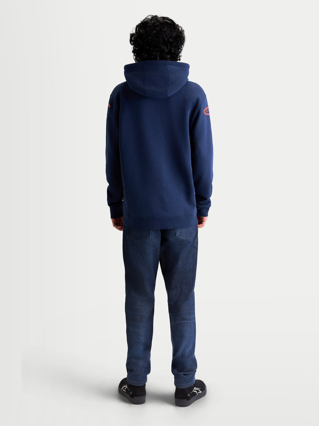 Alpinestars Velocifier huvtröja, sportig huvtröja i fleece, mörkblå med röda axellogotyper, ryggvy på modell, mjuk bomulls- och återvunnen polyesterblandning för avslappnad stil utanför hojen.
