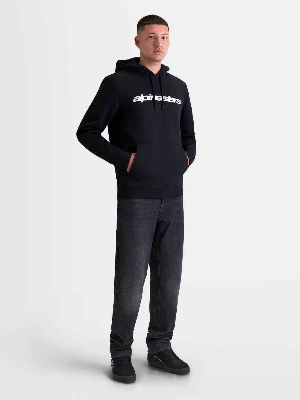 Alpinestars Race Wordmark huvtröja, sportig fleecehuvtröja för herr, svart och vit, vit linjär logotyp på bröstet, huva med dragsko och känguruficka, racinginspirerad vardagsstil, visas på modell
