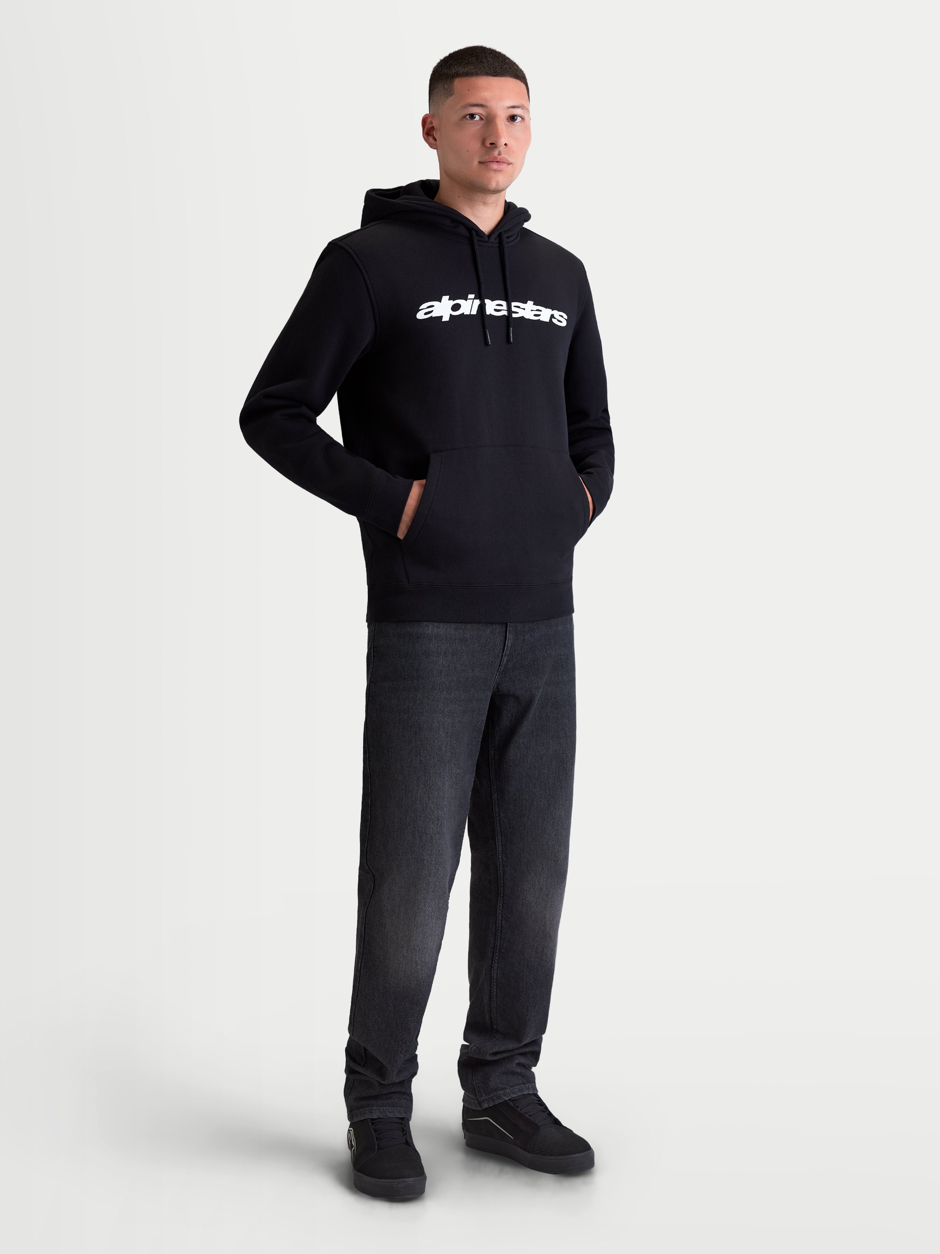 Alpinestars Race Wordmark huvtröja, sportig fleecehuvtröja för herr, svart och vit, vit linjär logotyp på bröstet, huva med dragsko och känguruficka, racinginspirerad vardagsstil, visas på modell