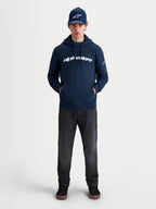 Alpinestars Race Wordmark huvtröja, sportig huvtröja i fleece, marinblå och vit, stor vit wordmark-logotyp på bröstet och Ageless-logotyp på ärmen, livsstilsbild på modell för en avslappnad motorsport-inspirerad look.