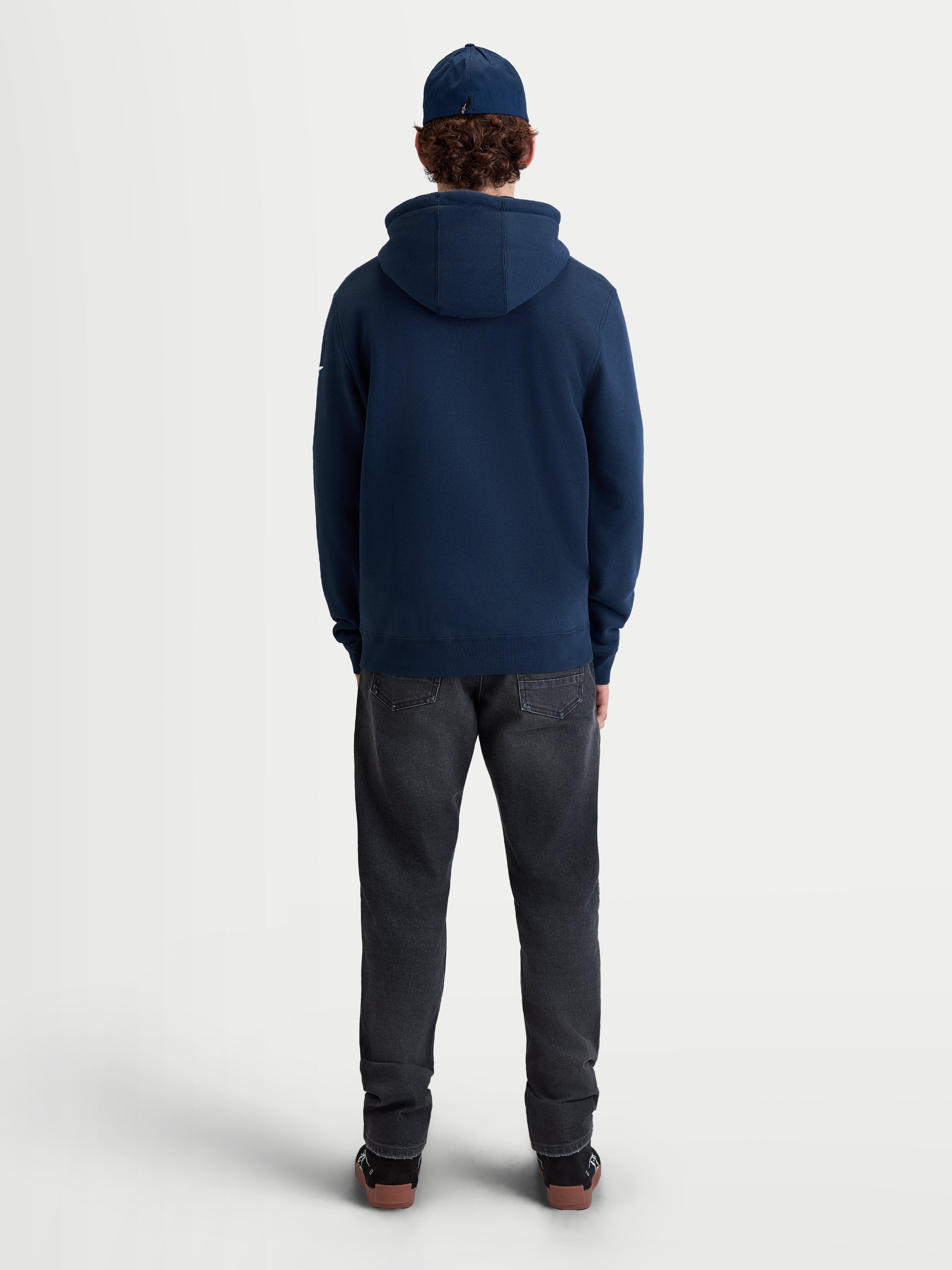Alpinestars Race Wordmark huvtröja, sportig huvtröja i fleece för vardagsbruk, sedd bakifrån på modell, mörkblå, tillverkad av en mjuk blandning av bomull och återvunnen polyester med självfodrad huva och ribbad fåll.