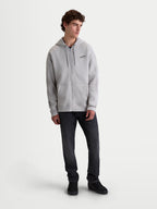 Alpinestars Entity Oversized huvtröja, fleece med dragkedja, unisex, cementgrå, premium bomullsblandning med avslappnad oversized passform, Vislon-dragkedja, känguruficka och broderad logotyp, visas på modell för vardagsbruk.