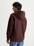 Alpinestars Entity Oversized huvtröja, sportig livsstilshuvtröja för herr, brun, återvunnen bomullsblandning, ryggvy på modell som visar den oversized silhuetten och huvans detaljer.