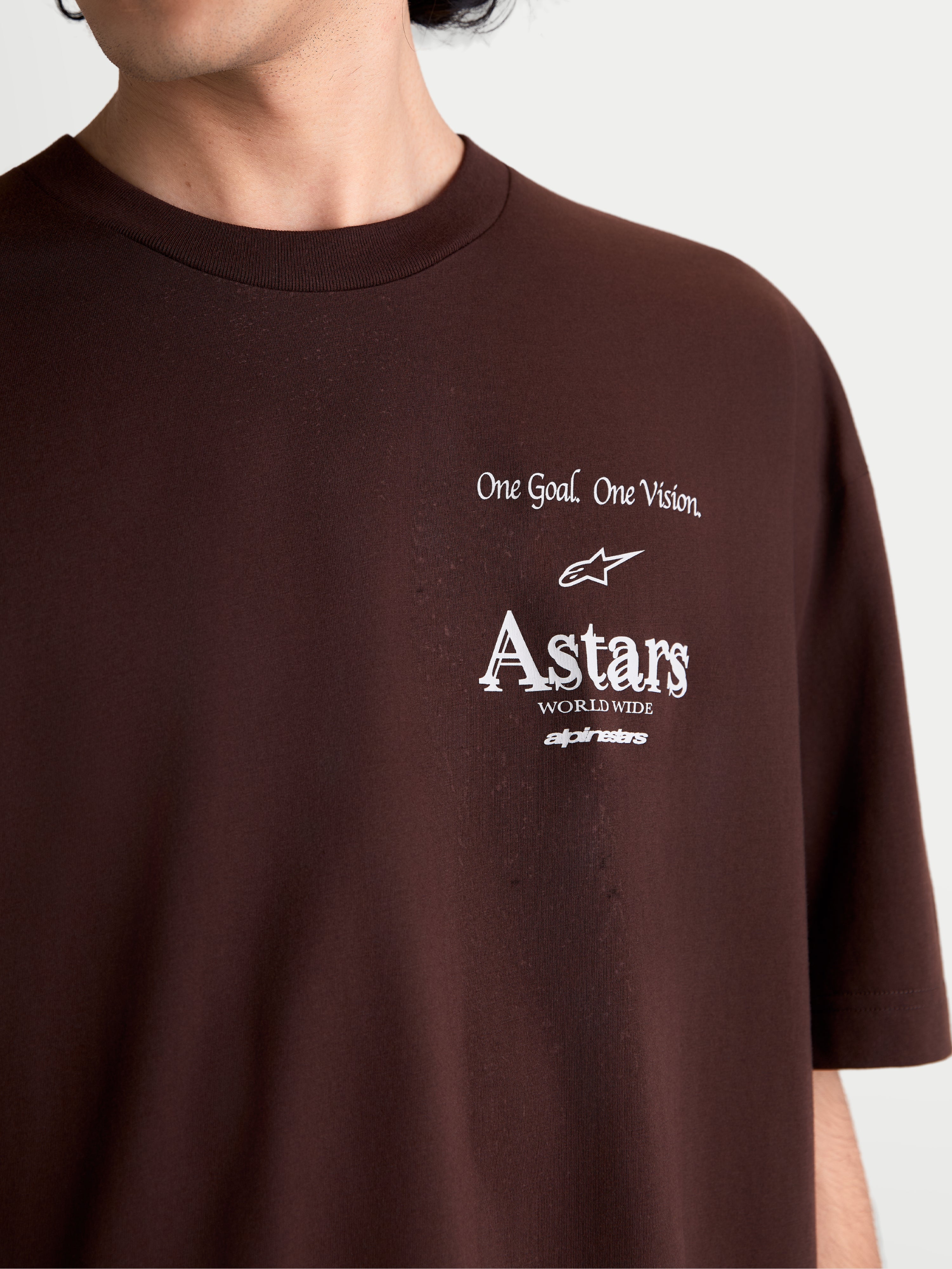 Alpinestars Post Oversized CSF t-shirt, kortärmad sportswear-t-shirt, brun, närbild med vit bröstgrafik med One Goal. One Vision. och Astars worldwide-logotyp, mjuk bomulls- och polyesterblandning.