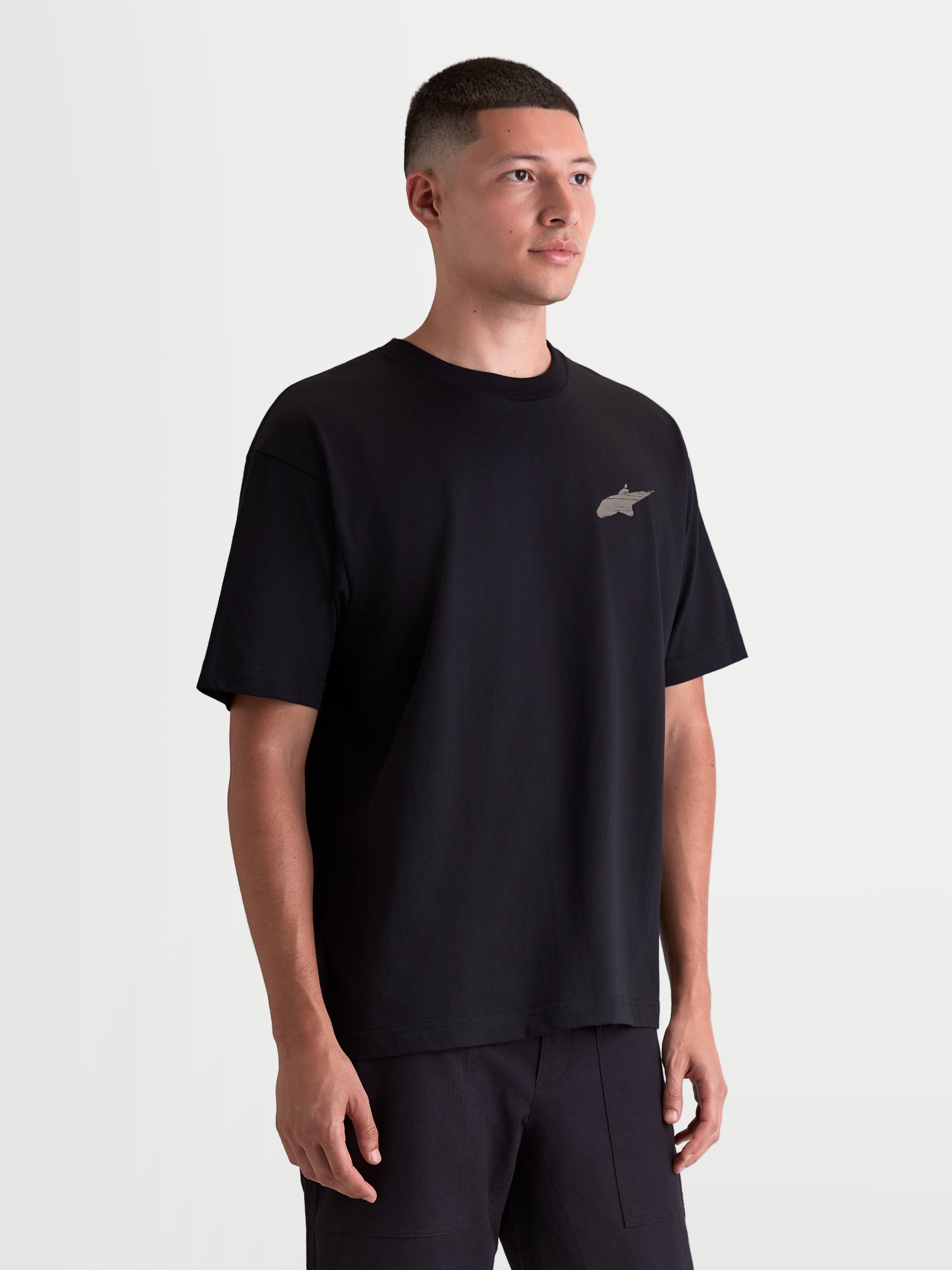 Alpinestars Checkback Oversized CSF Tee, Men's Sportswear Short Sleeve T-shirt, Black, on-model view featuring a relaxed oversized fit and small front Astars logo, premium cotton blend, motorsport-inspired lifestyle apparel.