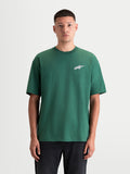 Alpinestars Checkback Oversized CSF t-shirt, grön kortärmad t-shirt för herrar, framifrån på modell, med avslappnad oversized passform och den ikoniska Astars-logotypen på bröstet, vardaglig motorsportinspirerad topp i bomulls- och polyesterblandning.