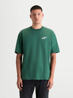 Alpinestars Checkback Oversized CSF t-shirt, grön kortärmad t-shirt för herrar, framifrån på modell, med avslappnad oversized passform och den ikoniska Astars-logotypen på bröstet, vardaglig motorsportinspirerad topp i bomulls- och polyesterblandning.