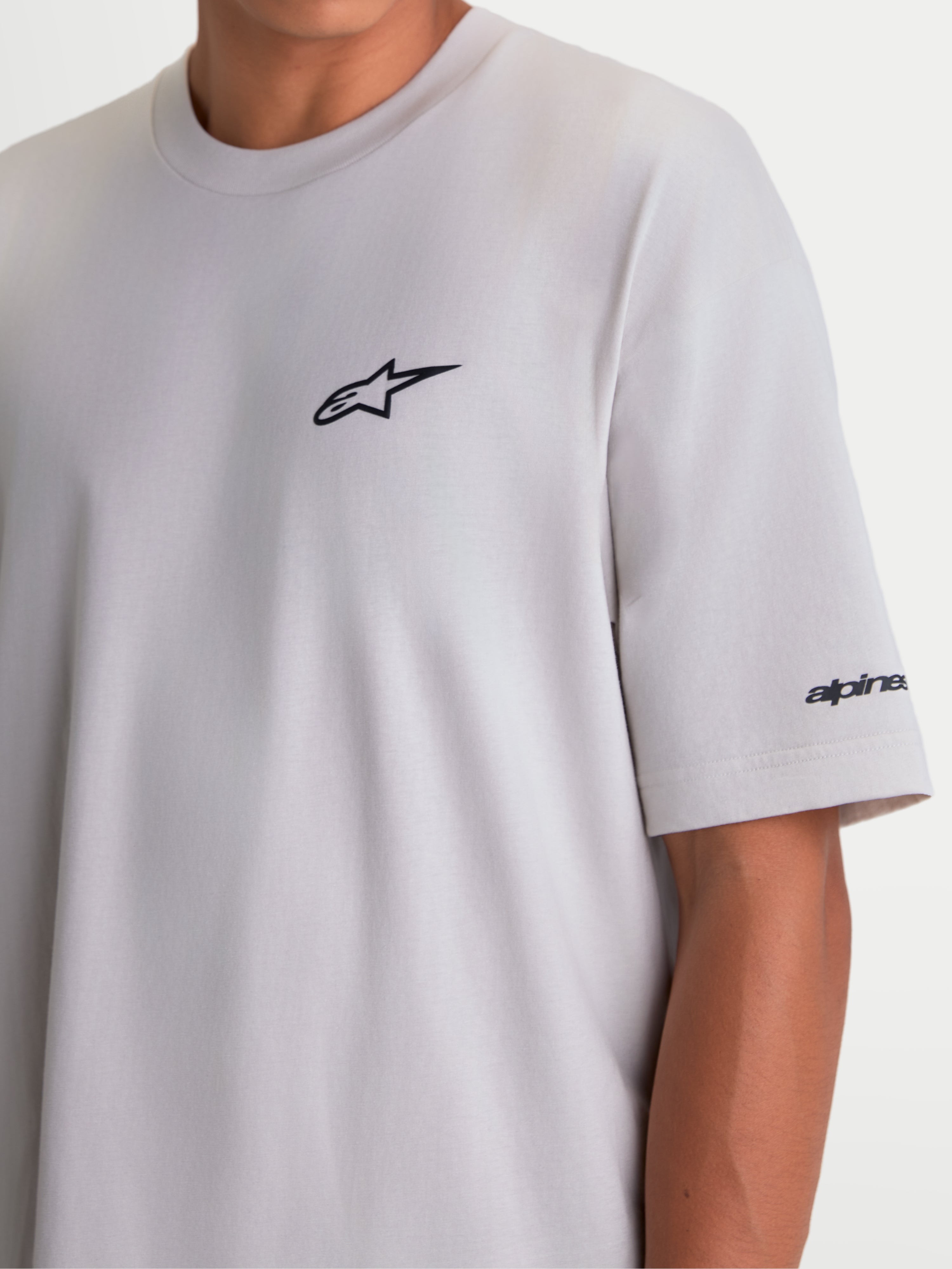 Alpinestars Mandate Oversized CSF t-shirt, kortärmad sportswear-modell för herr och dam, cementgrå med svart pufftryckt Astars-logotyp på bröstet och ordgrafik på ärmen, oversized passform för avslappnad komfort.