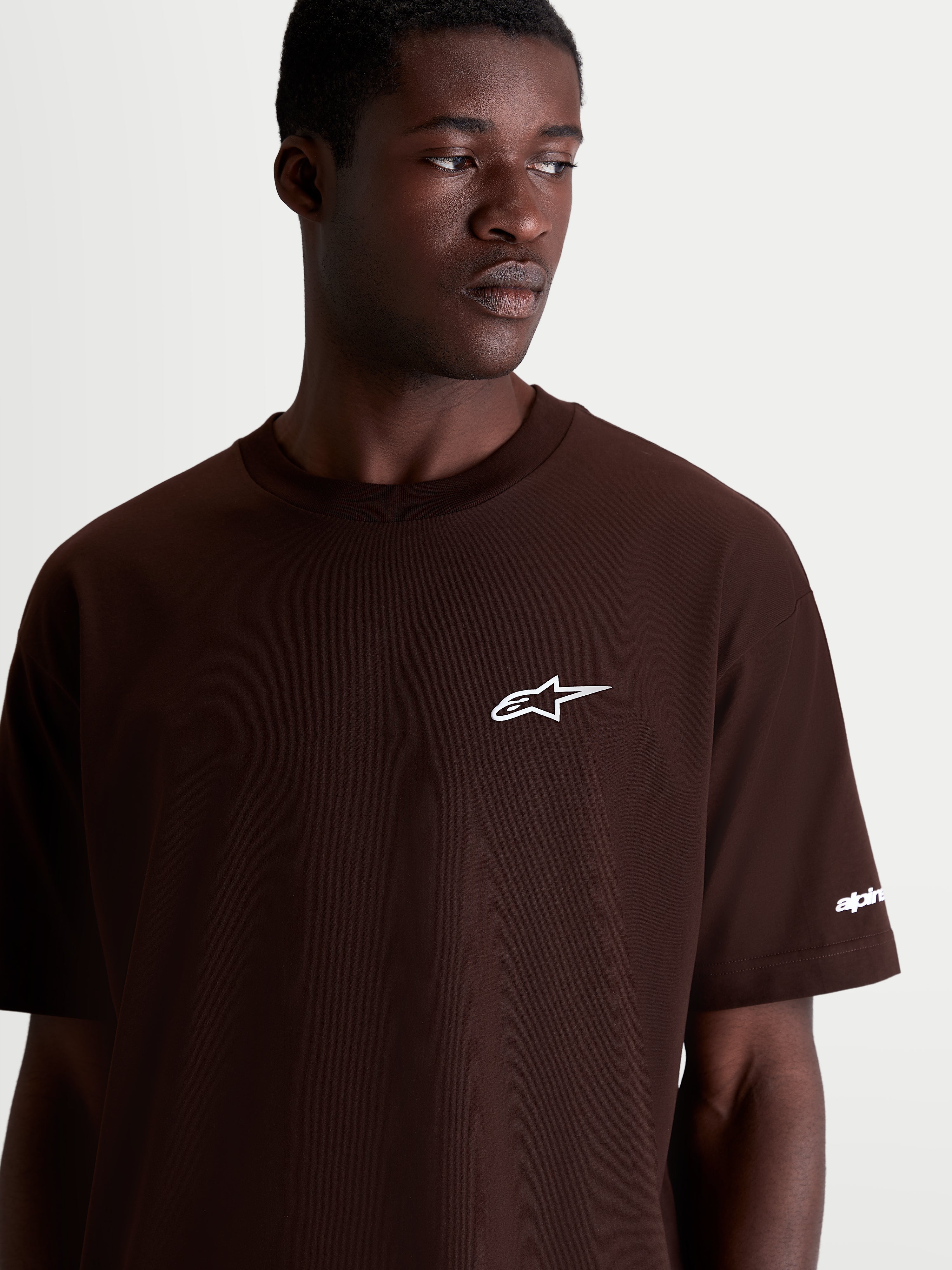 Alpinestars Mandate Oversized CSF t-shirt, brun kortärmad sportswear t-shirt med vit pufftryckt Astars-logotyp på bröstet, oversized passform, mjuk bomullsblandning, detaljbild på modell.