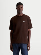 Alpinestars Mandate Oversized CSF t-shirt, brun kortärmad t-shirt bärs av en man, vit pufftryckt Astars-logotyp på bröstet och grafik på ärmen, avslappnad oversized passform, sportswear i bomullsblandning