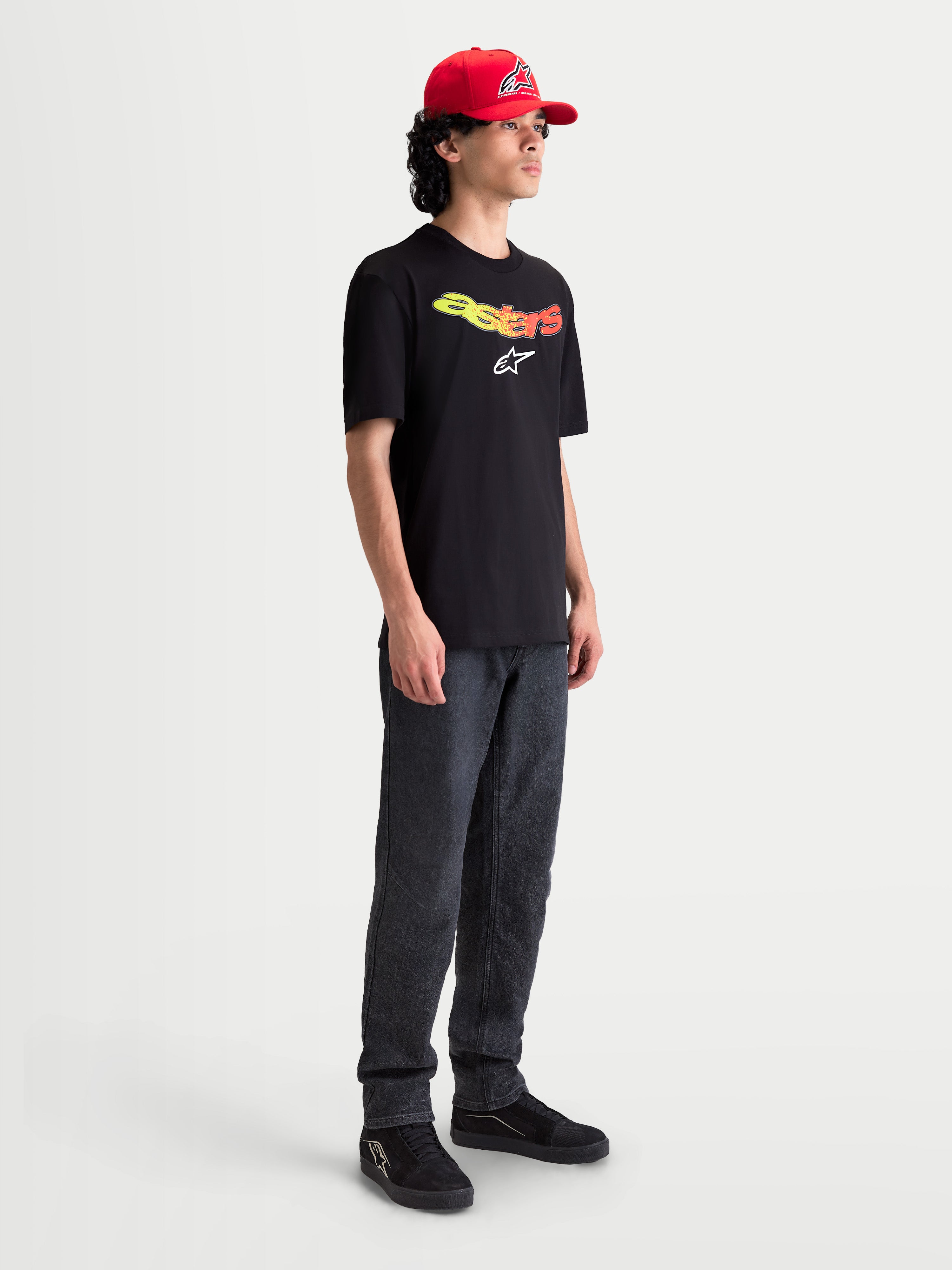 Alpinestars Elliptogrit CSF t-shirt på modell, kortärmad svart sportswear t-shirt för herrar med gul och röd gradient Astars-logotyp och vit grafisk logotyp på bröstet, bekväm bomullsblandning för vardagsbruk.
