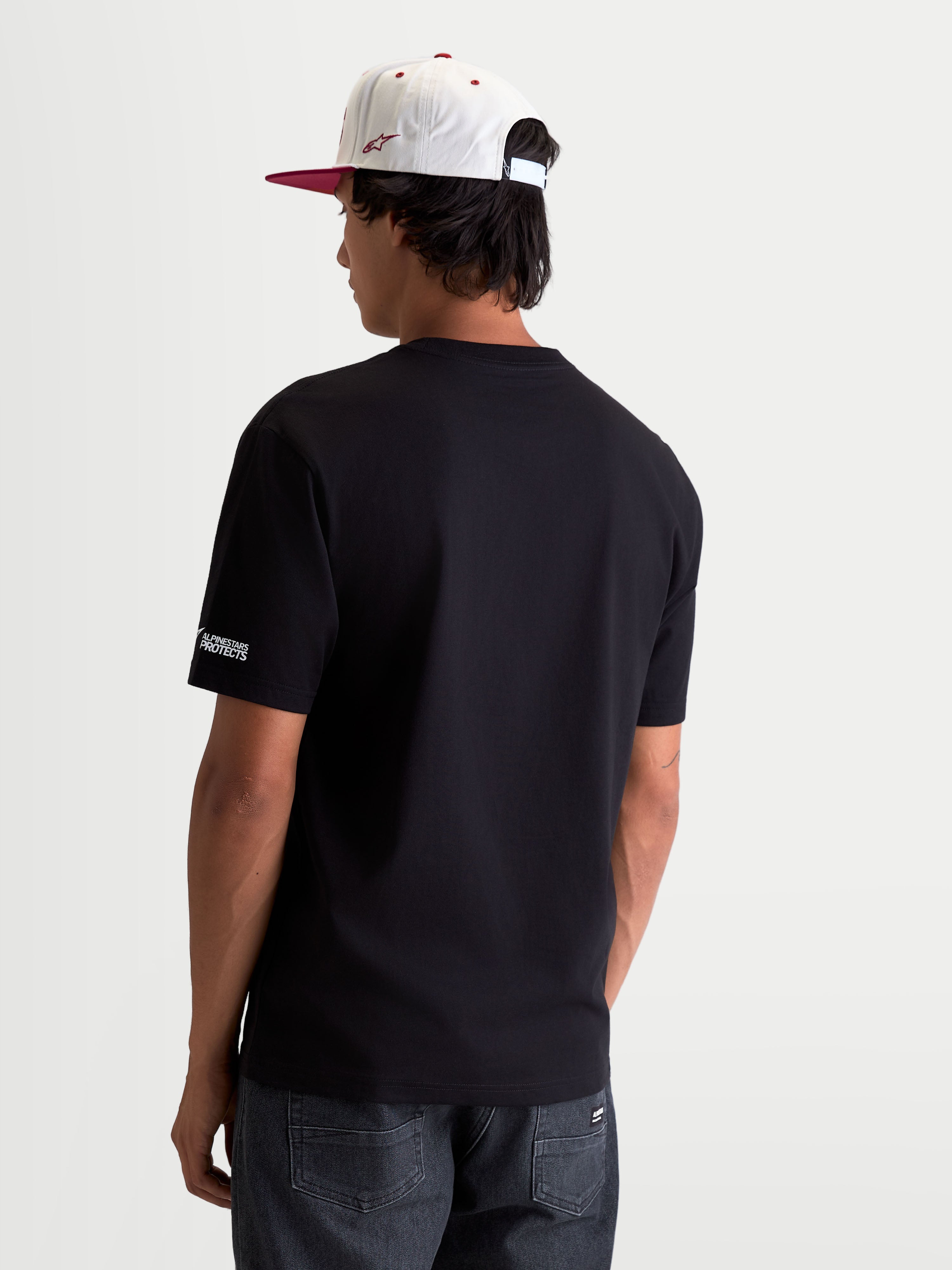 Alpinestars P1 CSF T-shirt, svart kortärmad t-shirt i motorsportstil, ryggvy på modell med vit Alpinestars PROTECTS-logotyp på ärmen, bekväm bomulls- och polyesterblandning.