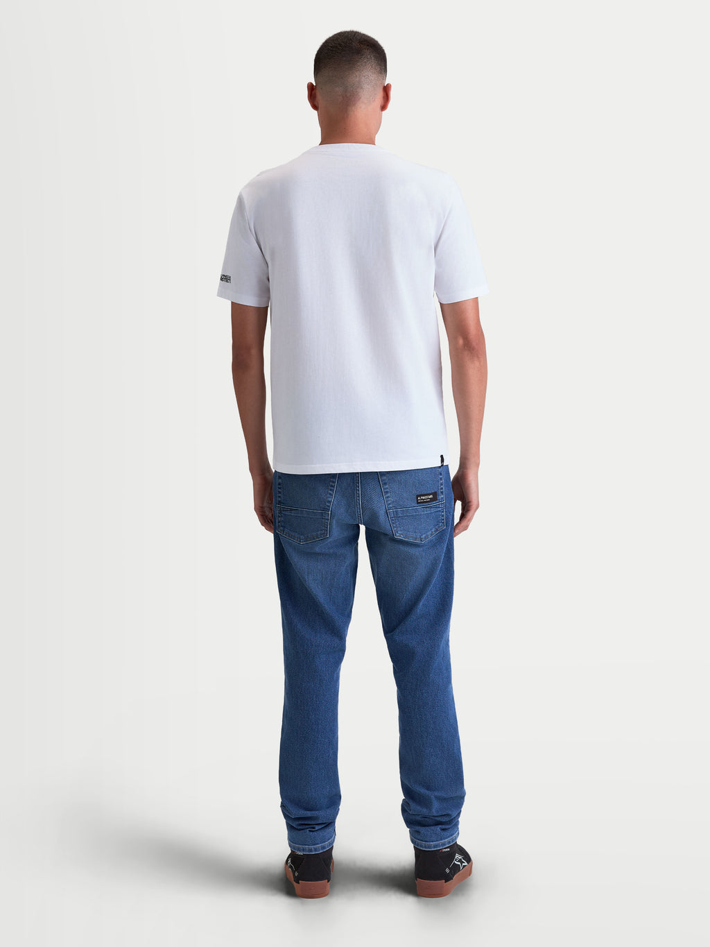 Alpinestars P1 CSF t-shirt, vit kortärmad sportswear-t-shirt i mjuk bomull-polyesterblandning, sedd bakifrån på modell, avslappnad motorsportstil