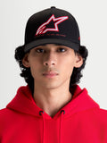Alpinestars Lineout keps, sportig baseballkeps med böjd skärm, svart med röd och vit broderad Astars-logotyp och One Goal One Vision-märkning, framifrån på modell i röd huvtröja, strukturerad twillkonstruktion