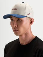 Alpinestars County Canvas Hat, sportswear cap in sand and blue, worn by a model, featuring curved bill and embroidered Astars logo