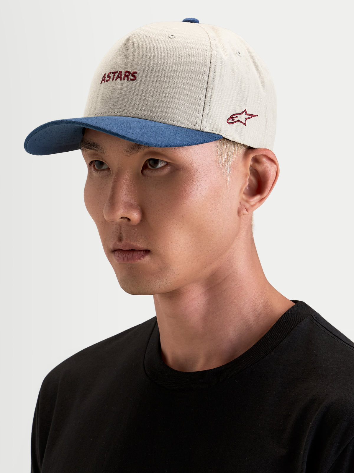 Alpinestars County Canvas Hat, sportswear cap in sand and blue, worn by a model, featuring curved bill and embroidered Astars logo