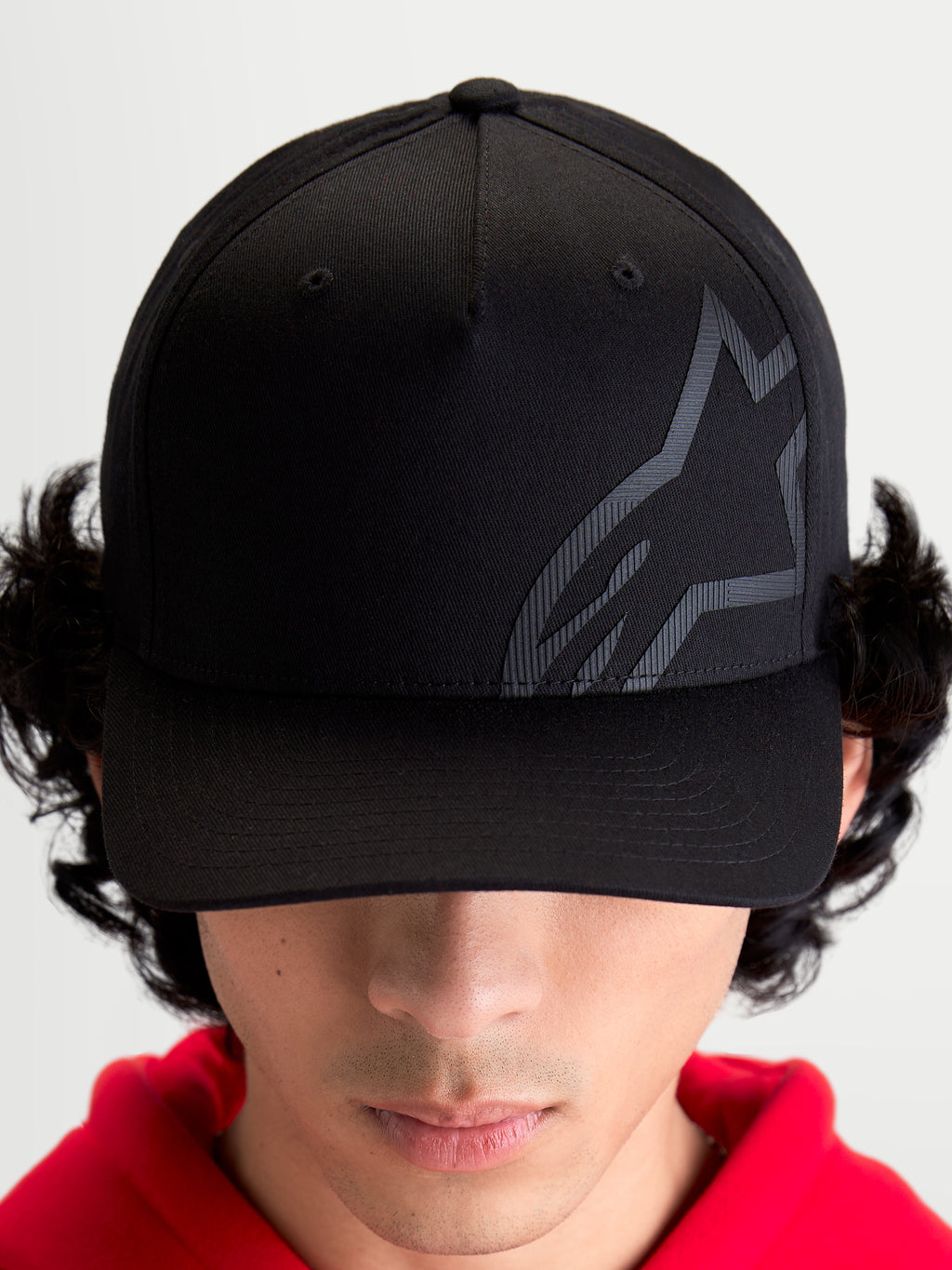 Alpinestars Maze keps, motorsportinspirerad keps i svart twill med texturerad Astars-logotyp, böjd skärm och strukturerad krona, framifrån på modell.